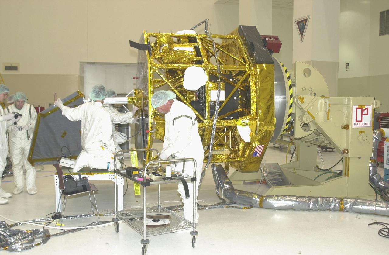 KENNEDY SPACE CENTER, FLA. - Workers in the Spacecraft Assembly and Encapsulation Facility 2 prepare the Comet Nucleus Tour (CONTOUR) spacecraft for another stage of installing solar panels. The spacecraft will provide the first detailed look into the heart of a comet -- the nucleus. The spacecraft will fly as close as 60 miles (100 kilometers) to at least two comets and will take the sharpest pictures yet of the nucleus while analyzing the gas and dust that surround these rocky, icy building blocks of the solar system. Launch of CONTOUR aboard a Boeing Delta II rocket is scheduled for July 1 from Launch Pad 17-A, Cape Canaveral Air Force Station