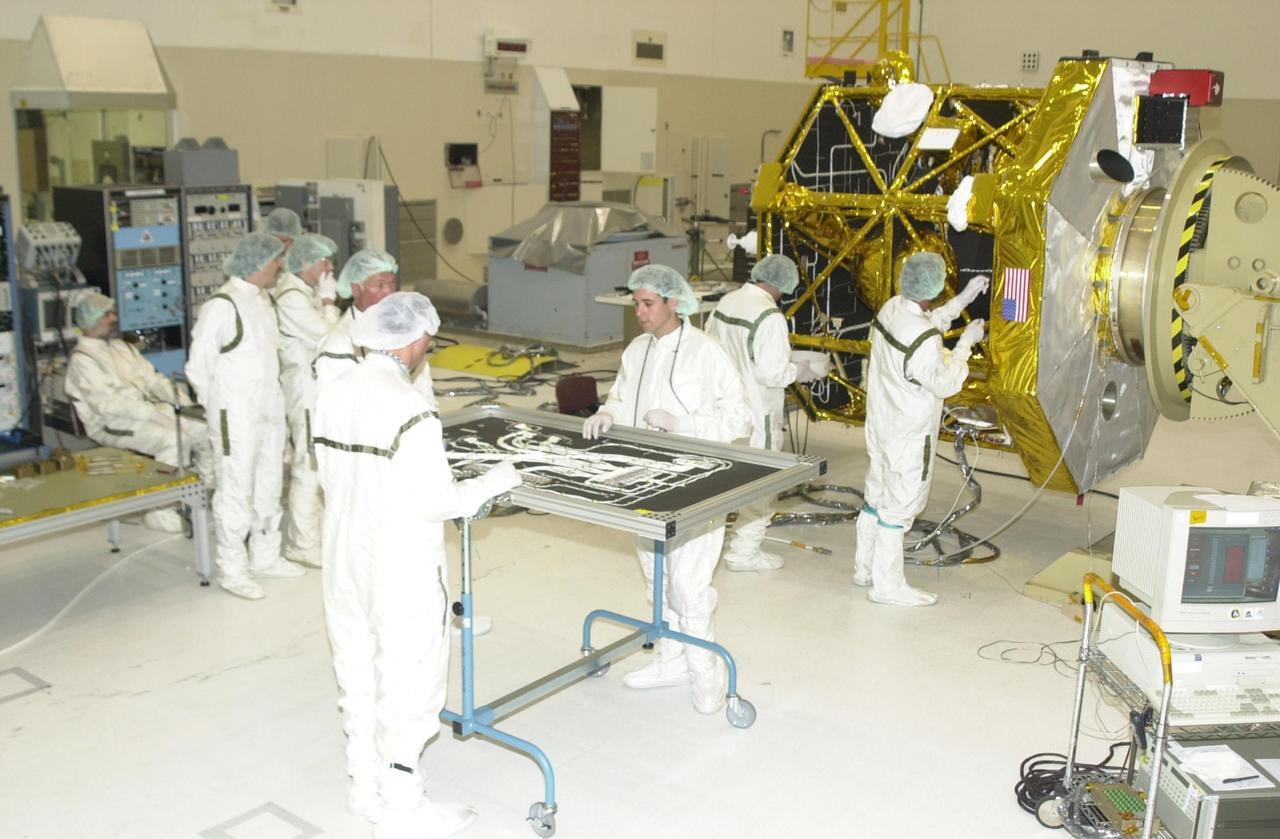 KENNEDY SPACE CENTER, FLA. -- Workers in the Spacecraft Assembly and Encapsulation Facility 2 prepare a solar panel and the Comet Nucleus Tour (CONTOUR) spacecraft (in the background) for installation of the panel. The spacecraft will provide the first detailed look into the heart of a comet -- the nucleus. The spacecraft will fly as close as 60 miles (100 kilometers) to at least two comets and will take the sharpest pictures yet of the nucleus while analyzing the gas and dust that surround these rocky, icy building blocks of the solar system.  Launch of CONTOUR aboard a Boeing Delta II rocket is scheduled for July 1 from Launch Pad 17-A, Cape Canaveral Air Force Station