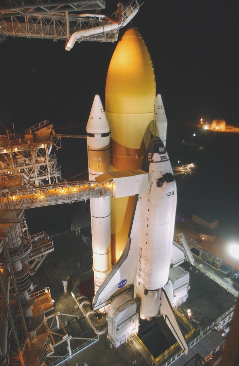 KENNEDY SPACE CENTER, FLA. - After rollback of the Rotating Service Structure, Space Shuttle Endeavour is bathed in light. Seen above the orange external tank behind Endeavour is the "beanie cap," or vent hood assembly at the end of the gaseous oxygen vent arm. The orbiter access arm extends to the cockpit area of Endeavour. At the end of the arm is the White Room, , an environmental chamber that provides crew access into the orbiter. STS-111 is the second Utilization Flight to the International Space Station, carrying the Multi-Purpose Logistics Module Leonardo, the Mobile Base System (MBS), and a replacement wrist/roll joint for the Canadarm 2. Also onboard Space Shuttle Endeavour is the Expedition 5 crew who will replace Expedition 4 on board the Station. The MBS will be installed on the Mobile Transporter to complete the Canadian Mobile Servicing System, or MSS. The mechanical arm will then have the capability to "inchworm" from the U.S. Lab Destiny to the MSS and travel along the truss to work sites. Expedition 4 crew members will return to Earth with the STS-111 crew on Endeavour. Launch is scheduled at 7:44 p.m. EDT, May 30, 2002