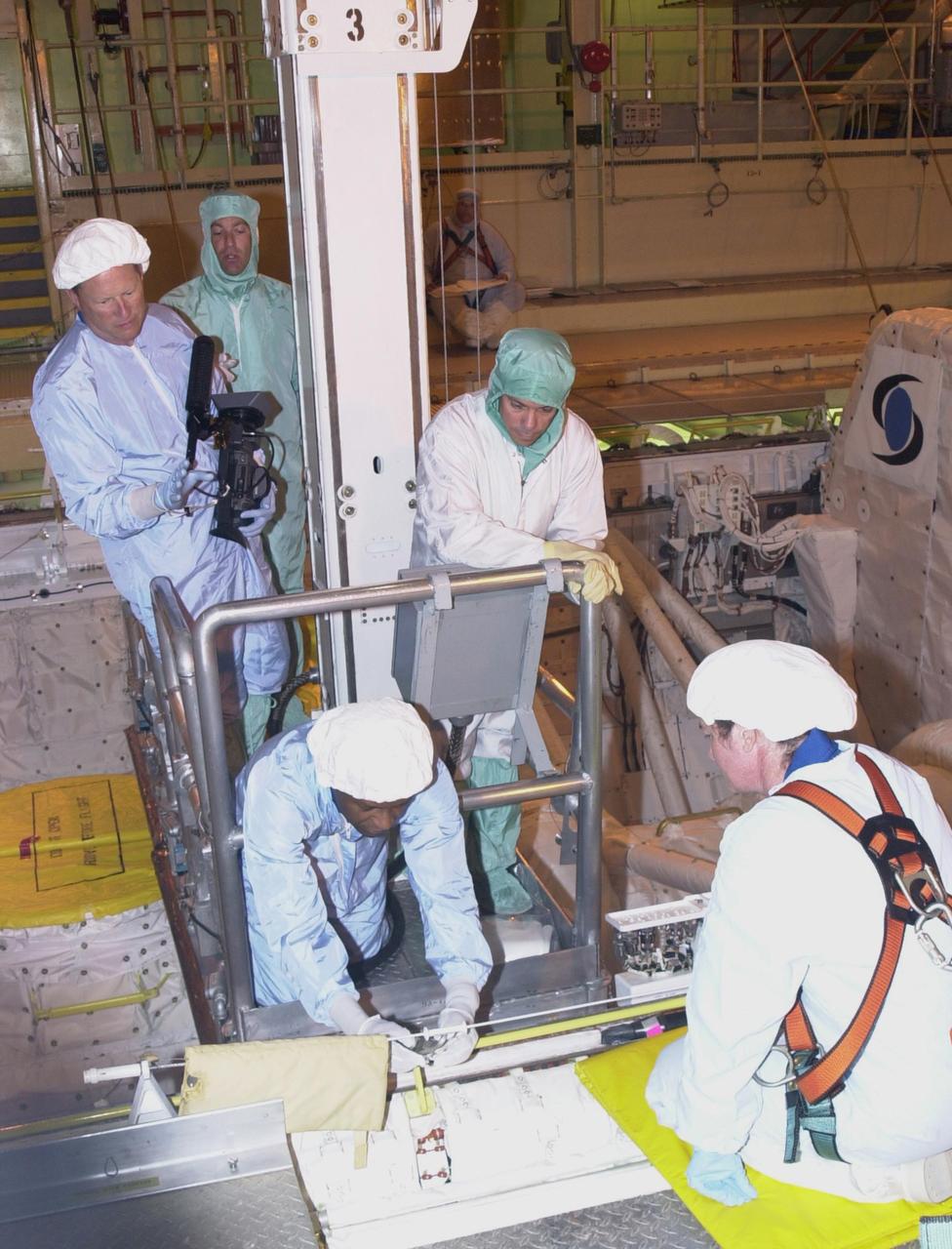KENNEDY SPACE CENTER, FLA. -- During Crew Equipment Interface Test activities,  STS-107 Payload Commander Michael Anderson looks over equipment from a lift in the payload bay of  Columbia while technicians (right and rear) look on.  Behind Anderson is Mission Specialist David Brown. STS-107 is a research mission, with the SHI Research Double Module (SHI/RDM), also known as SPACEHAB, as the primary payload, plus the Fast Reaction Experiments Enabling Science, Technology, Applications and Research (FREESTAR) that incorporates eight high priority secondary attached shuttle experiments.  STS-107 is scheduled to launch July 19, 2002
