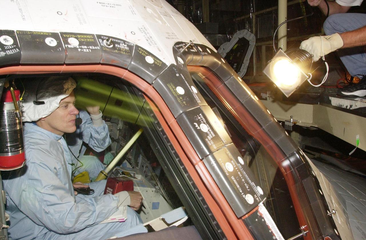 KENNEDY SPACE CENTER, FLA. - STS-107 Pilot William "Willie" McCool checks the window in Columbia during Crew Equipment Interface Test activities at KSC. The CEIT includes equipment and payload familiarization. STS-107 is a research mission, with the SHI Research Double Module (SHI/RDM), also known as SPACEHAB, as the primary payload, plus the Fast Reaction Experiments Enabling Science, Technology, Applications and Research (FREESTAR) that incorporates eight high priority secondary attached shuttle experiments. STS-107 is scheduled to launch July 19, 2002