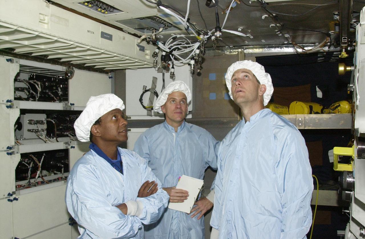 KENNEDY SPACE CENTER, FLA. --  STS-107 Payload Commander Michael Anderson (left), Pilot William "Willie" McCool (center) and Commander Rick Husband  (right) look over equipment in the SHI Research Double Module (SHI/RDM), part of the payload on the mission. .  They are taking part in Crew Equipment Interface Test activities, which include equipment and payload familiarization. A research mission, STS-107 also will carry the Fast Reaction Experiments Enabling Science, Technology, Applications and Research (FREESTAR) that incorporates eight high priority secondary attached shuttle experiments.  STS-107 is scheduled to launch July 19, 2002