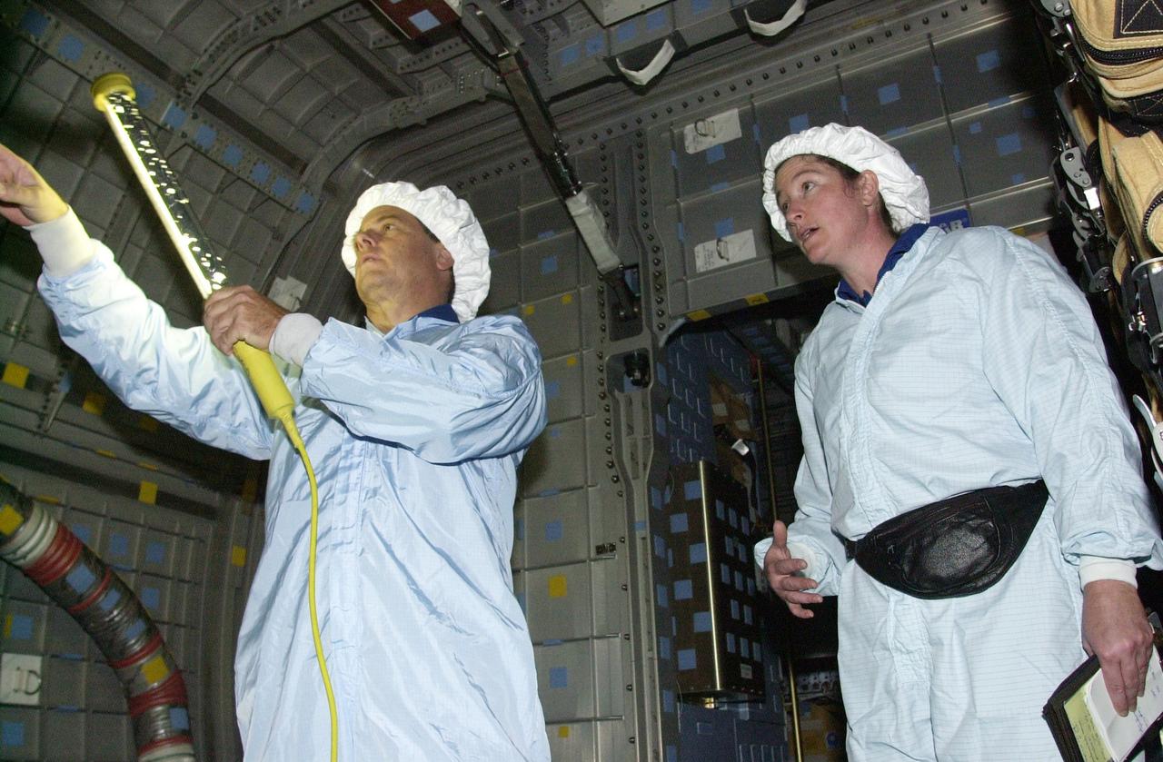 KENNEDY SPACE CENTER, FLA. - STS-107 Mission Specialists Ilan Ramon, with the Israeli Space Agency, and Laurel Clark check out equipment in the SHI Research Double Module (SHI/RDM), part of the payload on the mission. They are taking part in Crew Equipment Interface Test activities, which include equipment and payload familiarization. A research mission, STS-107 also will carry the Fast Reaction Experiments Enabling Science, Technology, Applications and Research (FREESTAR) that incorporates eight high priority secondary attached shuttle experiments. STS-107 is scheduled to launch July 19, 2002