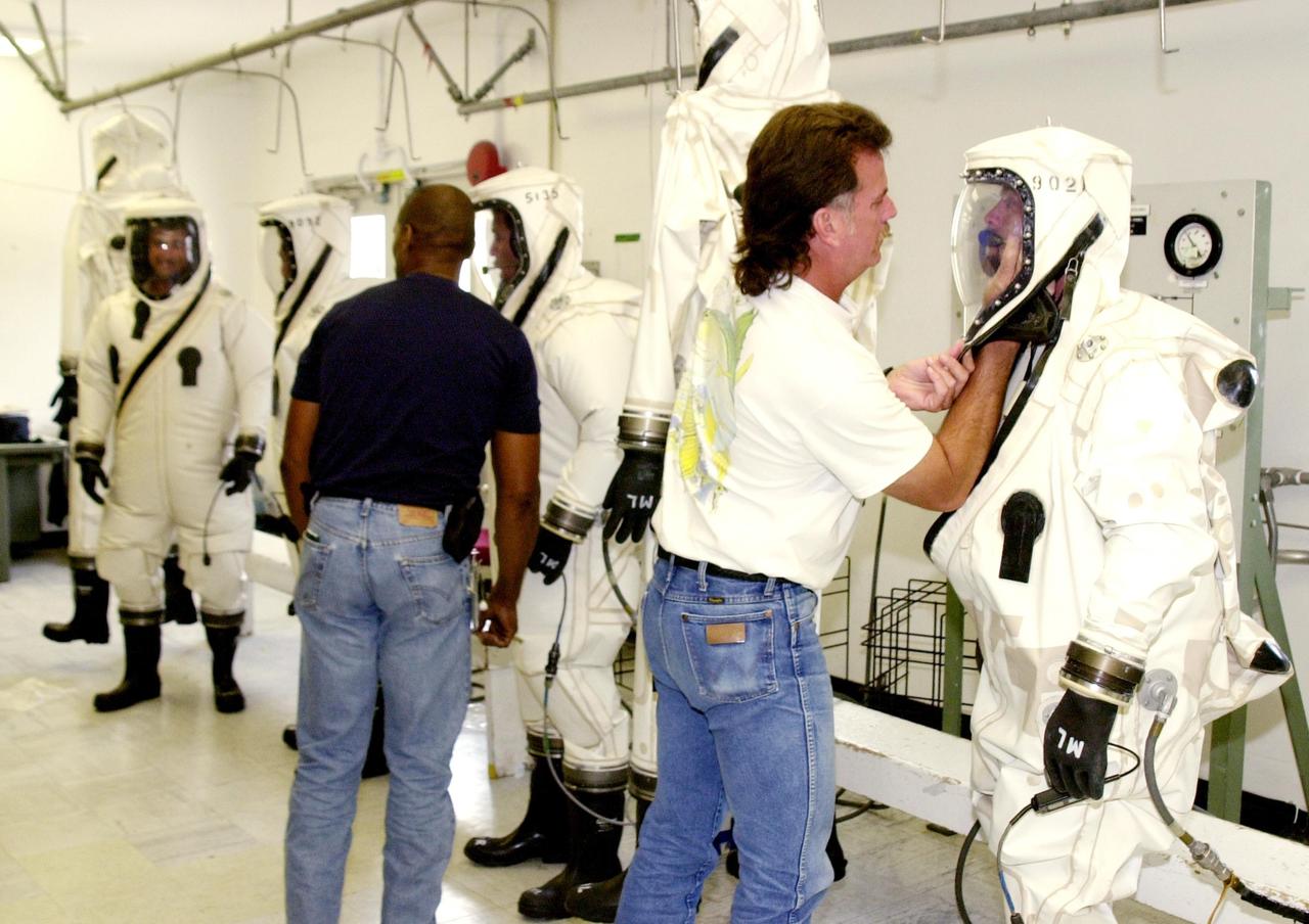 KENNEDY SPACE CENTER, FLA. -- Workers finish donning SCAPE suits for the fueling of the Comet Nucleus Tour (CONTOUR) spacecraft in the Spacecraft Assembly and Encapsulation Facility 2 (SAEF-2). SCAPE refers to Self-Contained Atmospheric Protective Ensemble.  CONTOUR will provide the first detailed look into the heart of a comet -- the nucleus. Flying as close as 60 miles (100 kilometers) to at least two comets, the spacecraft will take the sharpest pictures yet of a nucleus while analyzing the gas and dust that surround them.  CONTOUR is scheduled for launch aboard a Boeing Delta II rocket July 1, 2002, from Launch Complex 17-A, Cape Canaveral Air Force Station