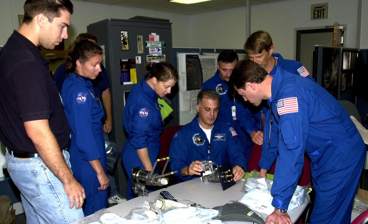KENNEDY SPACE CENTER, FLA. - The STS-112 crew looks over equipment in the Space Station Processing Facility as part of the Crew Equipment Interface Test. From left are a technician, Mission Specialist Sandra Magnus, Pilot Pamela Melroy, Mission Specialists David Wolf (seated), Fyodor Yurchikhin and Piers Sellers, and Commander Jeffrey Ashby (in front). Yurchikhin is with the Russian Space Agency. Mission STS-112 will be ferrying the S1 ITS to the International Space Station on its scheduled Aug. 22 flight. The S1 truss is the first starboard (right-side) truss segment, whose main job is providing structural support for the orbiting research facility's radiator panels that cool the Space Station's complex power system. The S1 truss segment also will house communications systems, external experiment positions and other subsystems. The S1 truss will be attached to the S0 truss