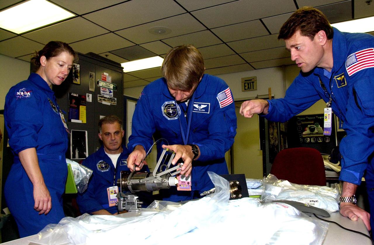 KENNEDY SPACE CENTER, FLA. -- The STS-112 crew looks over equipment in the Space Station Processing Facility as part of the Crew Equipment Interface Test. From left are Pilot Pamela Melroy, Mission Specialists David Wolf (seated) and Piers Sellers, and Commander Jeffrey Ashby. Mission STS-112 will be ferrying the S1 ITS to the International Space Station on its scheduled Aug. 22 flight. The S1 truss is the first starboard (right-side) truss segment, whose main job is providing structural support for the orbiting research facility's radiator panels that cool the Space Station's complex power system. The S1 truss segment also will house communications systems, external experiment positions and other subsystems. The S1 truss will be attached to the S0 truss