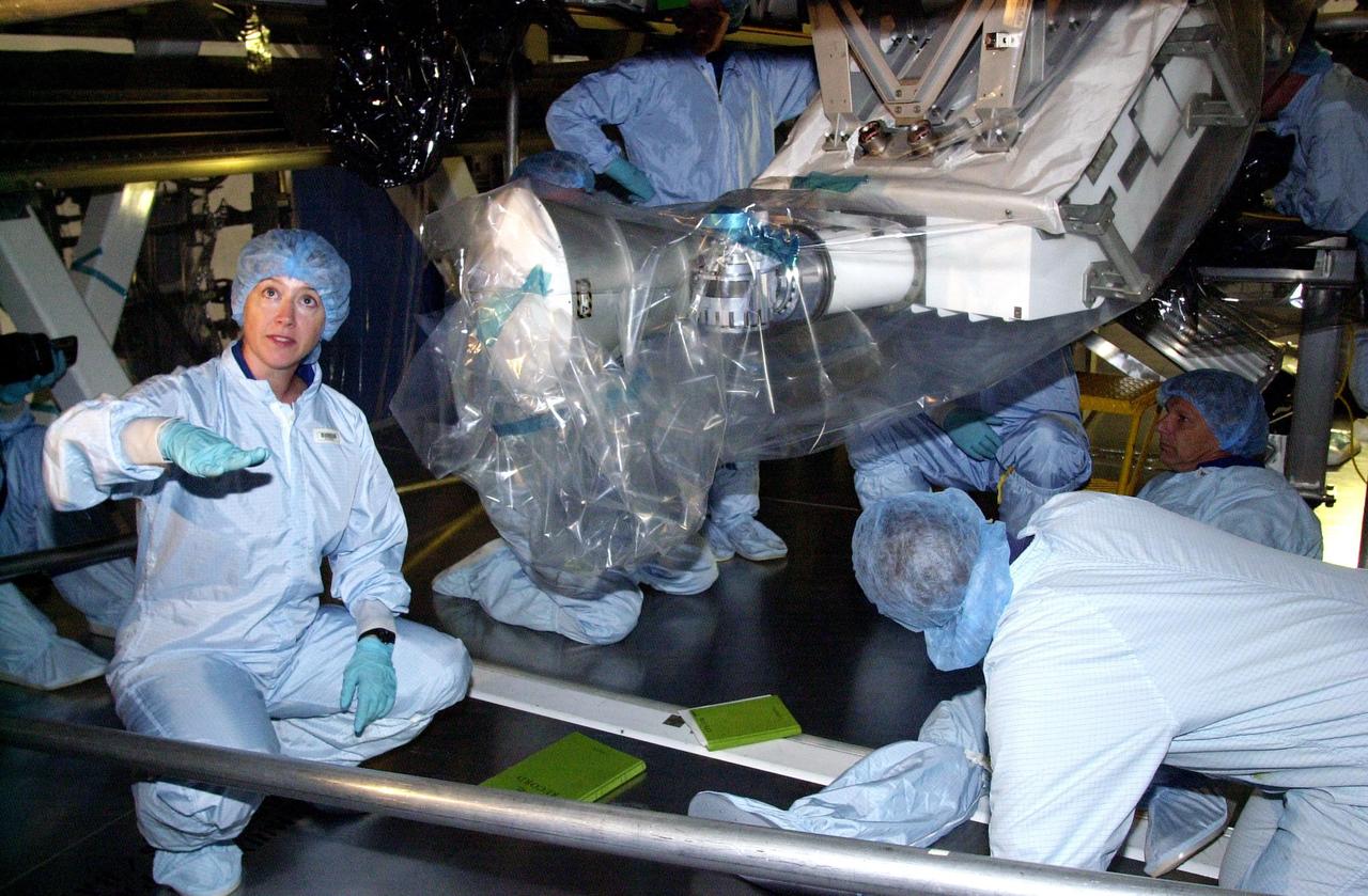 KENNEDY SPACE CENTER, FLA. -  STS-112 Pilot Pamela Melroy signals to someone off camera while behind her other crew members look over the S1 Integrated Truss Structure, part of the payload for the mission to the International Space Station. The S1 truss is the first starboard (right-side) truss segment, whose main job is providing structural support for the orbiting research facility's radiator panels that cool the Space Station's complex power system. The S1 truss segment also will house communications systems, external experiment positions and other subsystems.  The S1 truss will be attached to the S0 truss.  Launch of STS-112 is scheduled for Aug. 22, 2002