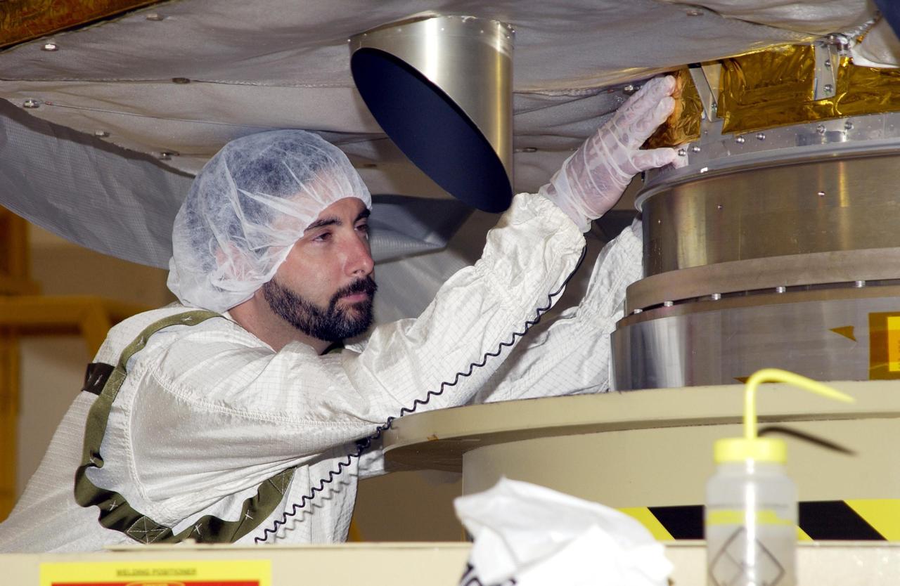 KENNEDY SPACE CENTER, FLA. -- A worker in the Space Assembly and Encapsulation Facility 2 (SAEF-2) checks the base of the Comet Nucleus Tour (CONTOUR) spacecraft before it is moved for mating with the upper stage of a Boeing Delta II rocket. CONTOUR will provide the first detailed look into the heart of a comet -- the nucleus. Flying as close as 60 miles (100 kilometers) to at least two comets, the spacecraft will take the sharpest pictures yet of a nucleus while analyzing the gas and dust that surround these rocky, icy building blocks of the solar system. Launch of CONTOUR aboard the Delta II is scheduled for July 1, 2002, from Launch Complex 17-A, Cape Canaveral Air Force Station