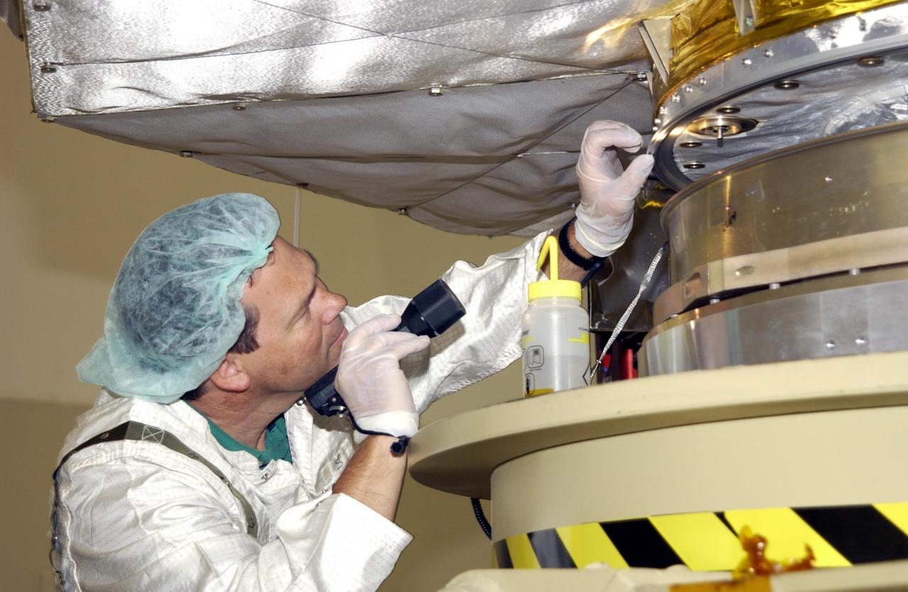 KENNEDY SPACE CENTER, FLA. -- A worker in the Space Assembly and Encapsulation Facility 2 (SAEF-2) checks the base of the Comet Nucleus Tour (CONTOUR) spacecraft before it is moved for mating with the upper stage of a Boeing Delta II rocket. CONTOUR will provide the first detailed look into the heart of a comet -- the nucleus. Flying as close as 60 miles (100 kilometers) to at least two comets, the spacecraft will take the sharpest pictures yet of a nucleus while analyzing the gas and dust that surround these rocky, icy building blocks of the solar system. Launch of CONTOUR aboard the Delta II is scheduled for July 1, 2002, from Launch Complex 17-A, Cape Canaveral Air Force Station