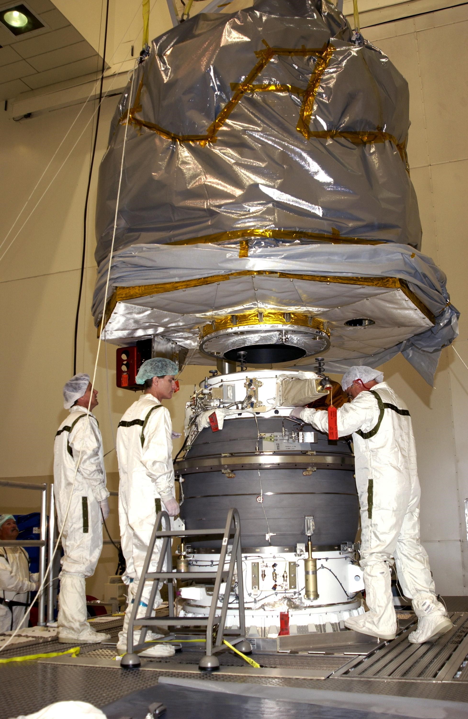 KENNEDY SPACE CENTER, FLA. --  Workers check the progress of the Comet Nucleus Tour (CONTOUR) spacecraft as it is lowered toward the upper stage of a Boeing Delta II rocket for mating. CONTOUR will provide the first detailed look into the heart of a comet -- the nucleus. Flying as close as 60 miles (100 kilometers) to at least two comets, the spacecraft will take the sharpest pictures yet of a nucleus while analyzing the gas and dust that surround these rocky, icy building blocks of the solar system.  Launch of CONTOUR aboard the Delta II is scheduled for July 1, 2002, from Launch Complex 17-A, Cape Canaveral Air Force Station