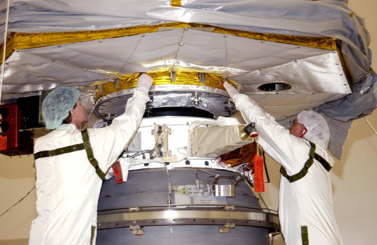 KENNEDY SPACE CENTER, FLA. -- Workers help guide the Comet Nucleus Tour (CONTOUR) spacecraft as it is lowered toward the upper stage of a Boeing Delta II rocket for mating. CONTOUR will provide the first detailed look into the heart of a comet -- the nucleus. Flying as close as 60 miles (100 kilometers) to at least two comets, the spacecraft will take the sharpest pictures yet of a nucleus while analyzing the gas and dust that surround these rocky, icy building blocks of the solar system.  Launch of CONTOUR aboard the Delta II is scheduled for July 1, 2002, from Launch Complex 17-A, Cape Canaveral Air Force Station