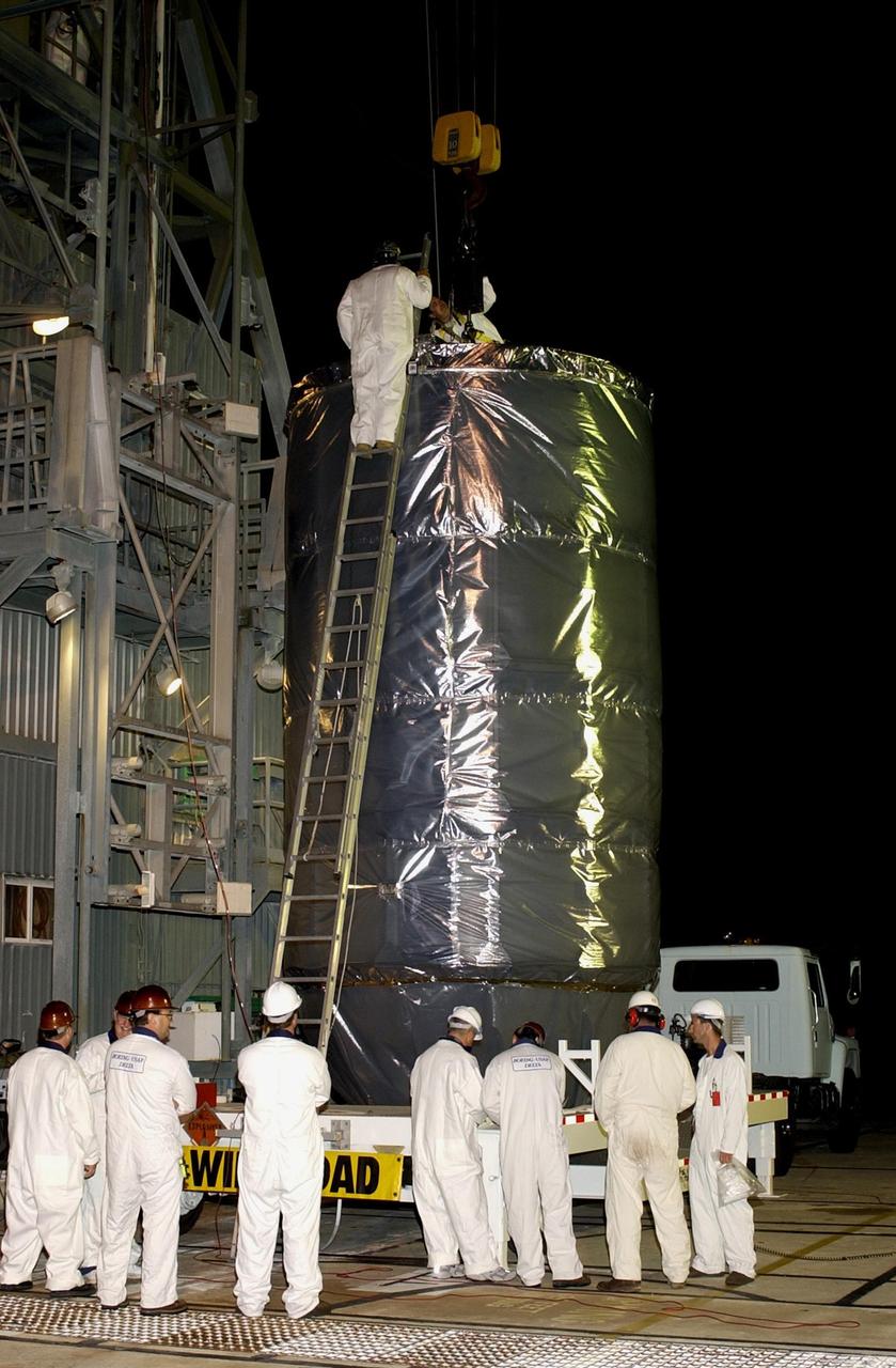 KENNEDY SPACE CENTER, FLA. -- On Launch Complex 17-A, Cape Canaveral Air Force Station, workers attach a crane to the top of the canister containing the Comet Nucleus Tour (CONTOUR) spacecraft. CONTOUR will be lifted up the gantry for encapsulation and mating with the launch vehicle. CONTOUR will provide the first detailed look into the heart of a comet -- the nucleus. Flying as close as 60 miles (100 kilometers) to at least two comets, the spacecraft will take the sharpest pictures yet of a nucleus while analyzing the gas and dust that surround these rocky, icy building blocks of the solar system. Launch of CONTOUR aboard a Boeing Delta II rocket is scheduled for July 1, 2002