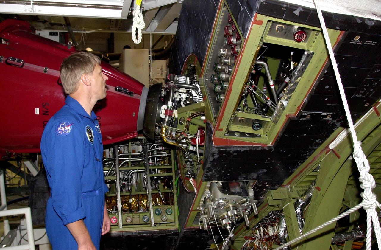 KENNEDY SPACE CENTER, FLA. - During a Crew Equipment Interface Test, STS-112 Mission Specialist Piers Sellers looks at the engine on Atlantis, the designated orbiter for the mission. On the 15th assembly flight to the International Space Station, Atlantis and crew will be ferrying the S1 Integrated Truss Structure. The S1 truss is the first starboard (right-side) truss segment, whose main job is providing structural support for the radiator panels that cool the Space Station's complex power system. The S1 truss segment also will house communications systems, external experiment positions and other subsystems.  The S1 truss will be attached to the S0 truss.  STS-112 is currently scheduled for launch Aug. 22, 2002