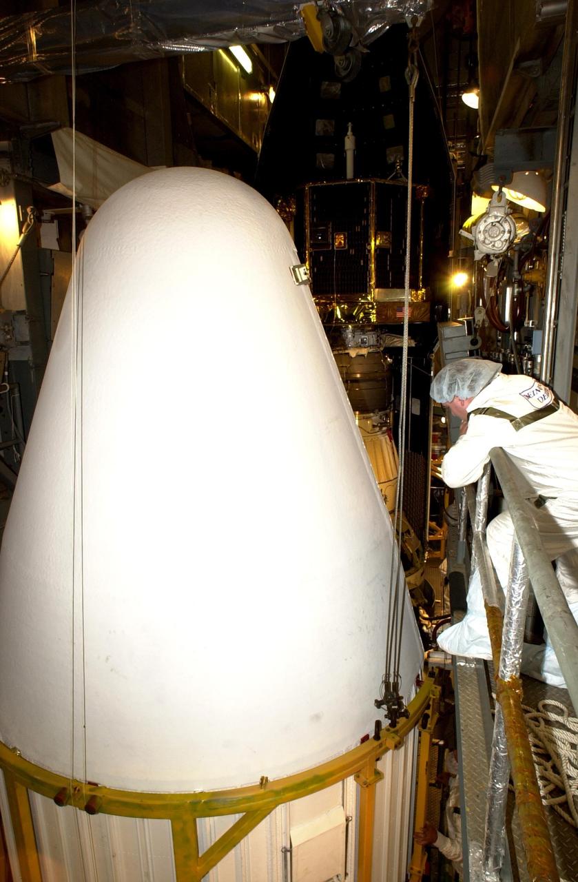 KENNEDY SPACE CENTER, FLA. -- At Launch Complex 17-A, Cape Canaveral Air Force Station, a worker watches as the second half of the fairing moves toward the Comet Nucleus Tour (CONTOUR) spacecraft in the background.  The fairing is the outer cover that protects the spacecraft during launch. Below the spacecraft is the Delta II rocket, the launch vehicle.  CONTOUR will provide the first detailed look into the heart of a comet -- the nucleus. Flying as close as 60 miles (100 kilometers) to at least two comets, the spacecraft will take the sharpest pictures yet of a nucleus while analyzing the gas and dust that surround them.  Launch of CONTOUR is scheduled for July 1, 2002