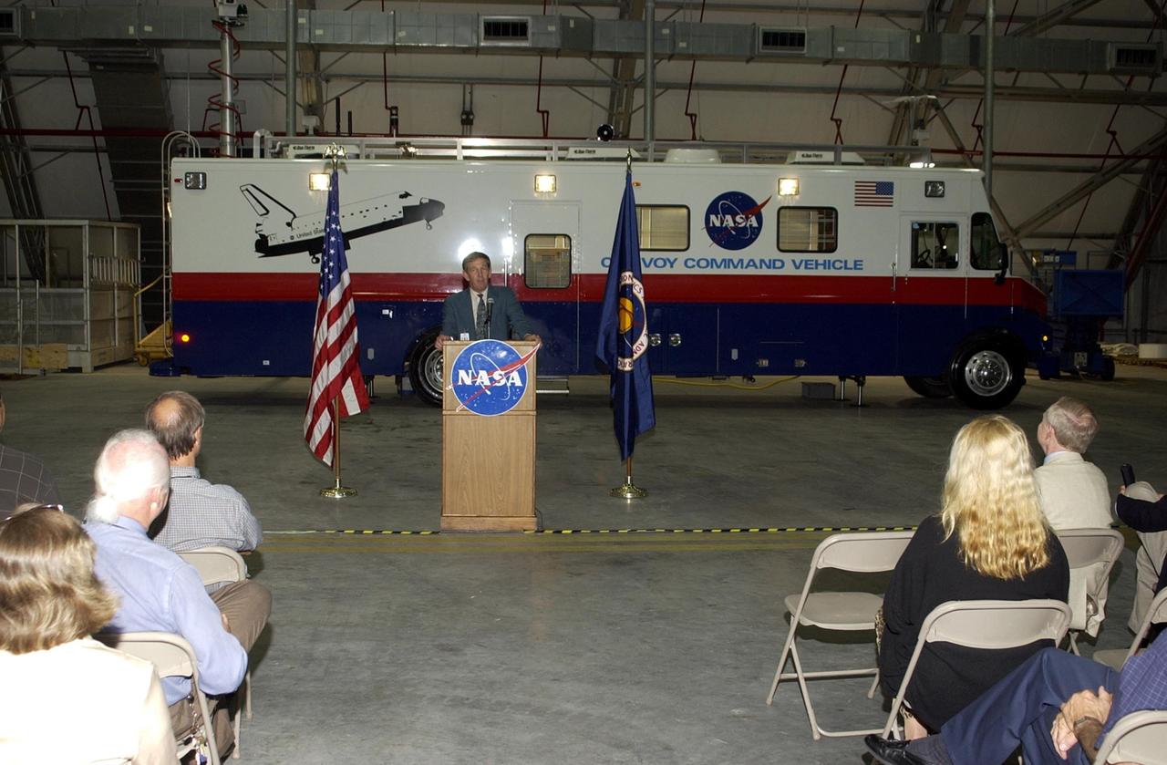 KENNEDY SPACE CENTER, FLA. --   United Space Alliance Chief Operating Officer Mike McCulley welcomes guests to the Landing Operations Facility and commissioning ceremony for the new Convoy Command Vehicle behind him. The new 40-foot vehicle is replacing a 15-year old model, and will be used following Shuttle landings as the prime vehicle to control critical communications between the orbiter, the crew and the Launch Control Center, to monitor the health of the Shuttle Orbiter systems and to direct convoy operations at the Shuttle Landing Facility. Upgrades and high-tech features incorporated into the design and development of this vehicle make it more reliable and efficient for the convoy crew. Seating capacity was increased from 4 to 12, and video recorders and television monitors were added to provide the convoy team with the maximum amount of visual information
