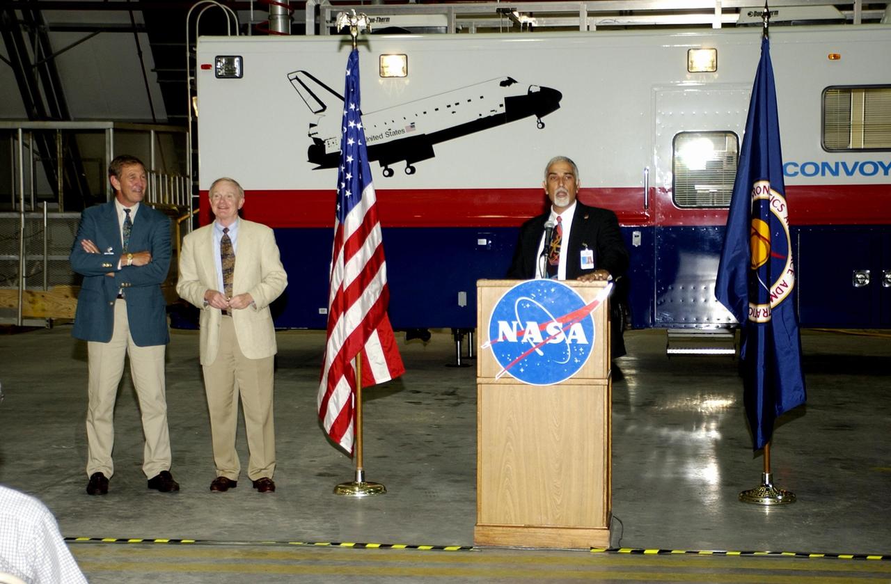 KENNEDY SPACE CENTER, FLA. --  During a commissioning ceremony for the new Convoy Command Vehicle (background), Tony Shibly, project manager, United Space Alliance, offers a few remarks to guests.  At left are USA Chief Operating Officer Mike McCulley and Center Director Roy Bridges Jr. The new 40-foot vehicle is replacing a 15-year old model, and will be used following Shuttle landings as the prime vehicle to control critical communications between the orbiter, the crew and the Launch Control Center, to monitor the health of the Shuttle Orbiter systems and to direct convoy operations at the Shuttle Landing Facility. Upgrades and high-tech features incorporated into the design and development of this vehicle make it more reliable and efficient for the convoy crew. Seating capacity was increased from 4 to 12, and video recorders and television monitors were added to provide the convoy team with the maximum amount of visual information