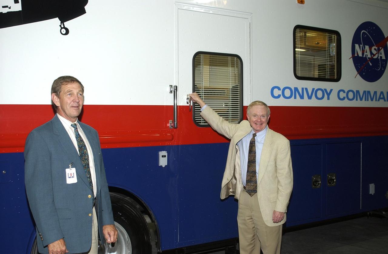 KENNEDY SPACE CENTER, FLA. - After opening remarks at a commissioning ceremony for the new Convoy Command Vehicle, Center Director Roy Bridges Jr. (right) gets ready to open the door for a tour of the vehicle. At left is United Space Alliance Chief Operating Officer Mike McCulley. The new 40-foot vehicle is replacing a 15-year old model, and will be used following Shuttle landings as the prime vehicle to control critical communications between the orbiter, the crew and the Launch Control Center, to monitor the health of the Shuttle Orbiter systems and to direct convoy operations at the Shuttle Landing Facility. Upgrades and high-tech features incorporated into the design and development of this vehicle make it more reliable and efficient for the convoy crew. Seating capacity was increased from 4 to 12, and video recorders and television monitors were added to provide the convoy team with the maximum amount of visual information