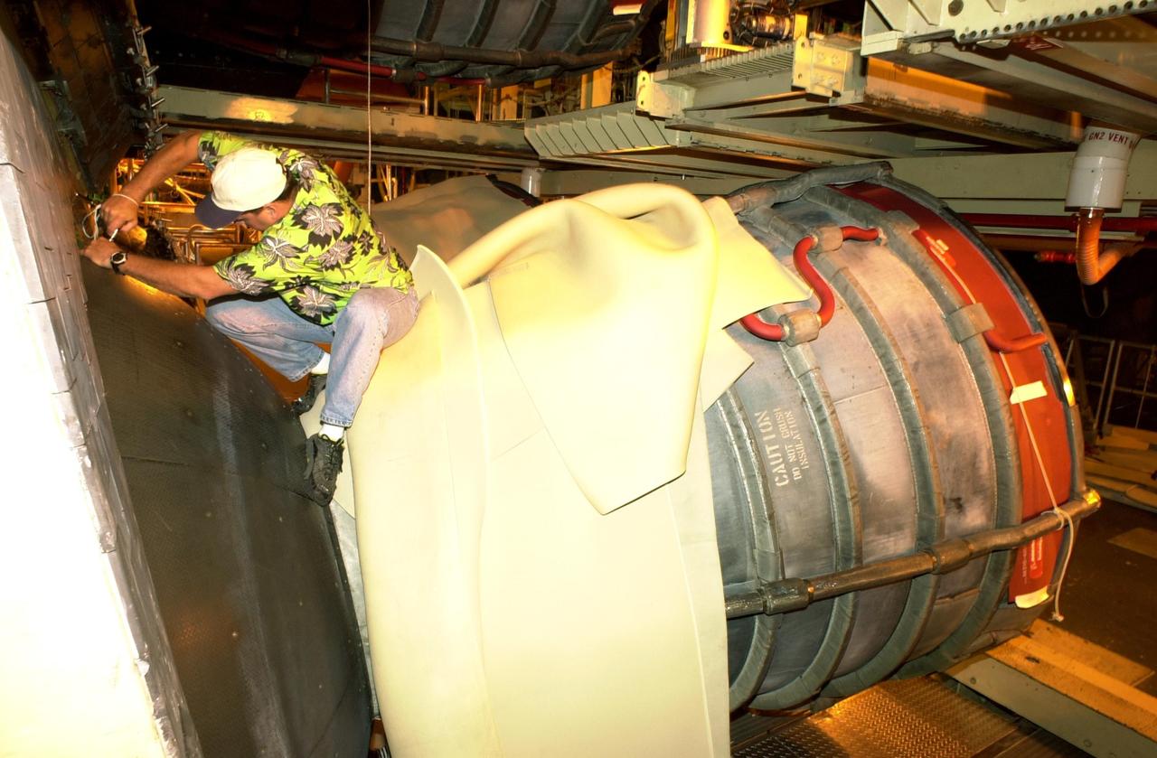 KENNEDY SPACE CENTER, FLA. - Doug Buford, with the Aft Engine shop, works at removing a heat shield on Columbia, in the Orbiter Processing Facility. After small cracks were discovered on the LH2 Main Propulsion System (MPS) flow liners in two other orbiters, program managers decided to move forward with inspections on Columbia before clearing it for flight on STS-107. After removal of the heat shields, the three main engines will be removed.  Inspections of the flow liners will follow.  The July 19 launch of Columbia on STS-107 has been delayed a few weeks