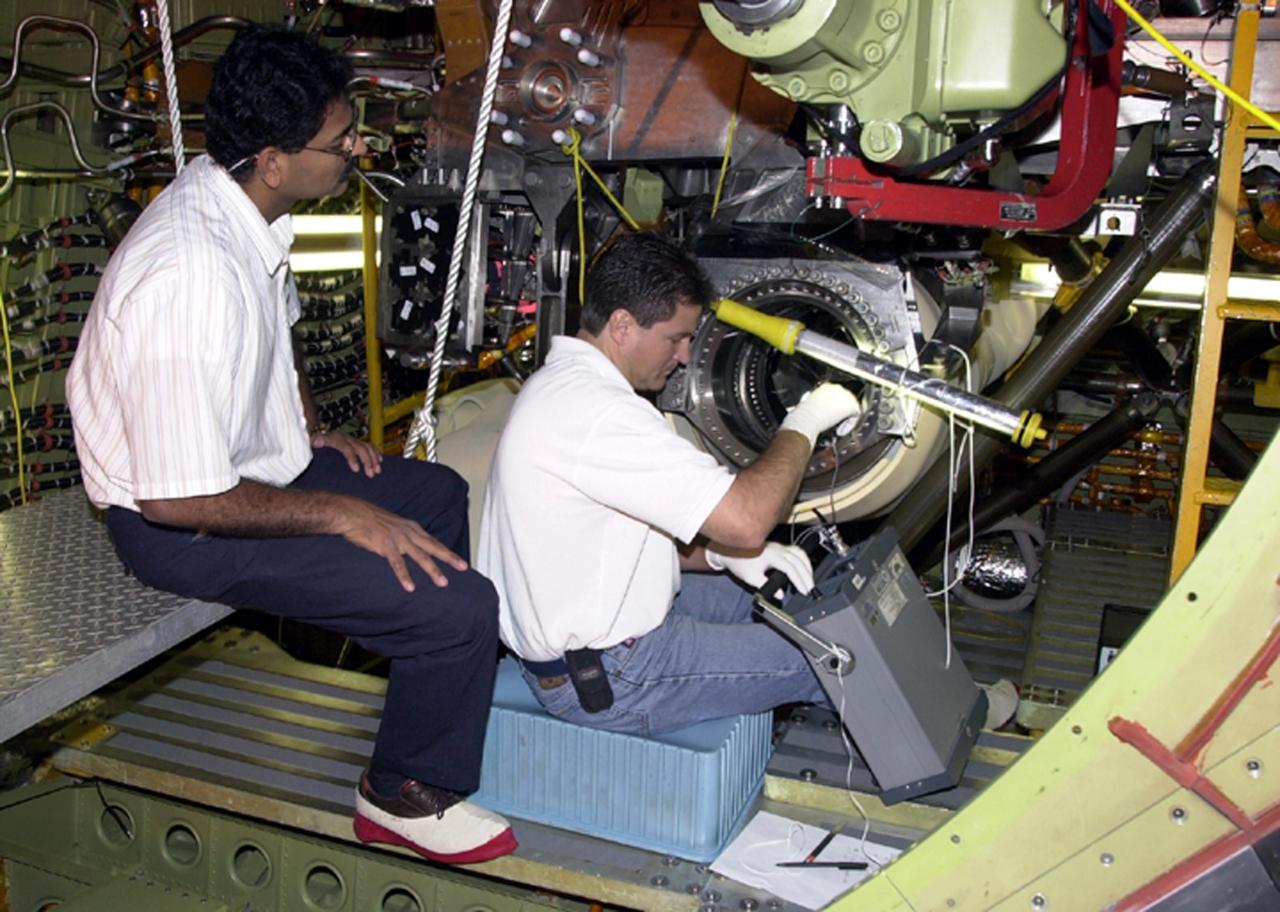 KENNEDY SPACE CENTER, FLA. --  After engine removal on Columbia, the flow line is being inspected by (left) A.J. Koshti, with The Boeing Co., and (right) Ken Tauer, with United Space Alliance. The inspection is the result of small cracks being discovered on the LH2 Main Propulsion System (MPS) flow liners in two other orbiters.  Program managers decided to conduct inspections on Columbia before clearing it for flight on STS-107. The July 19 launch of Columbia on STS-107 has been delayed a few weeks