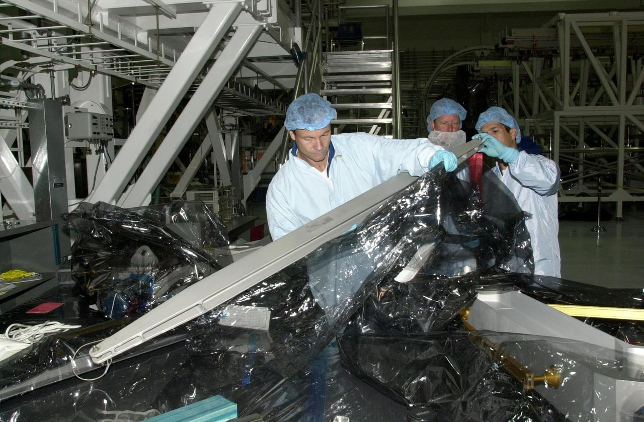 KENNEDY SPACE CENTER, FLA. -- Under the eyes of a technician (center), STS-113 crew members look over equipment involved in their mission during Crew Equipment Interface Test activities in the Space Station Processing Facility. At left is Mission Specialist Michael Lopez-Alegria; at right is Mission Specialist John Herrington. Part of the payload on mission STS-113 is the first port truss segment, P1 Truss, to be attached to the central truss segment, S0, on the International Space Station. Once delivered, the P1 truss will remain stowed until flight 12A.1. Launch date for STS-113 is under review.