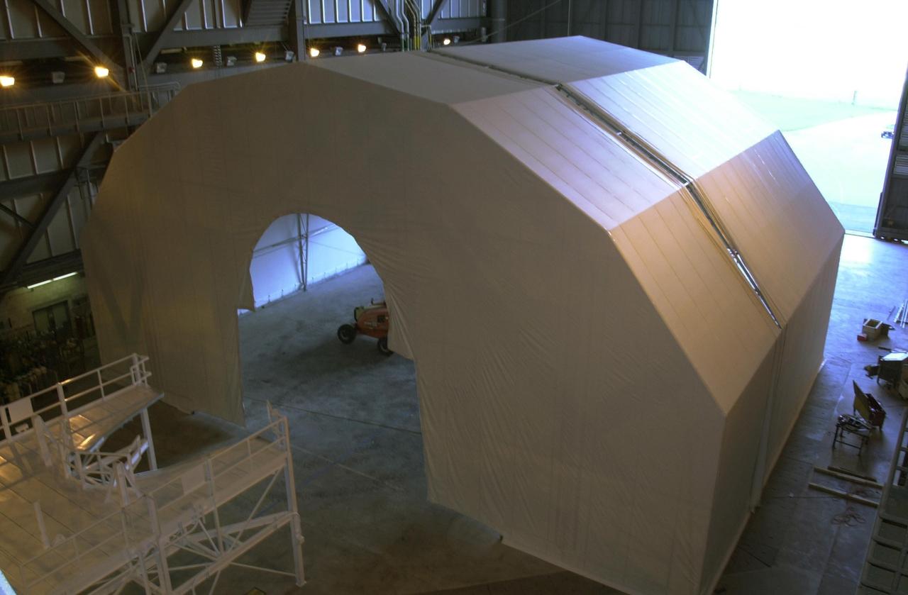 KENNEDY SPACE CENTER, FLA. -- -- In Vehicle Assembly Building (VAB) high bay 4, installation of a Payload Bay Door Drying Enclosure is in progress.  The enclosure will keep moisture from being absorbed into the graphite epoxy used on the payload bay doors of the Shuttle orbiters with the assistance of mini-Portable Purge Units (PPUs).  Once in operation, the enclosure will allow NASA the option to store an orbiter in the VAB bay up to 180 days in a "standby-to-stack" mode.
