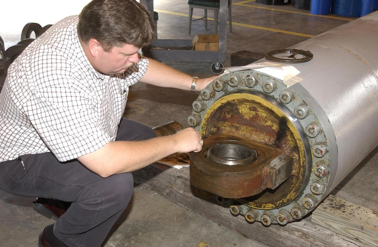KENNEDY SPACE CENTER, FLA. --   Perry Becker, an engineer with NASA, looks at a bearing from one of the jacking, equalization and leveling (JEL) cylinders on Crawler-Transporter No. 2. During inspections, technicians removed two of the 16 JEL cylinders on the vehicle to gain access to the bearings for routine maintenance and found three of the four bearings had cracks. Of the three bearings, two had extensive damage. Further eddy current inspections indicate that cracks are present on 15 of the bearings. There are 16 cylinders and 32 bearings per crawler. Although no cause for the cracks is known at this time, engineers are currently evaluating the situation to determine the most appropriate solution.