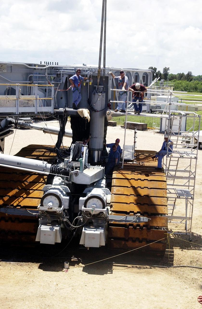 KENNEDY SPACE CENTER, FLA. -- Technicians hook a crane to a jacking, equalization and leveling (JEL) cylinder and bearing on Crawler-Transporter No. 2 in preparation for its removal. During routine maintenance inspections last week, technicians removed two of the 16 JEL cylinders on the crawler to gain access to the bearings and found three of the four bearings cracked. Further eddy current inspections indicated that cracks are present on 15 of the bearings. There are 16 cylinders and 32 bearings per crawler. Engineers are evaluating the situation to determine the cause of the cracks and an appropriate solution to the problem.