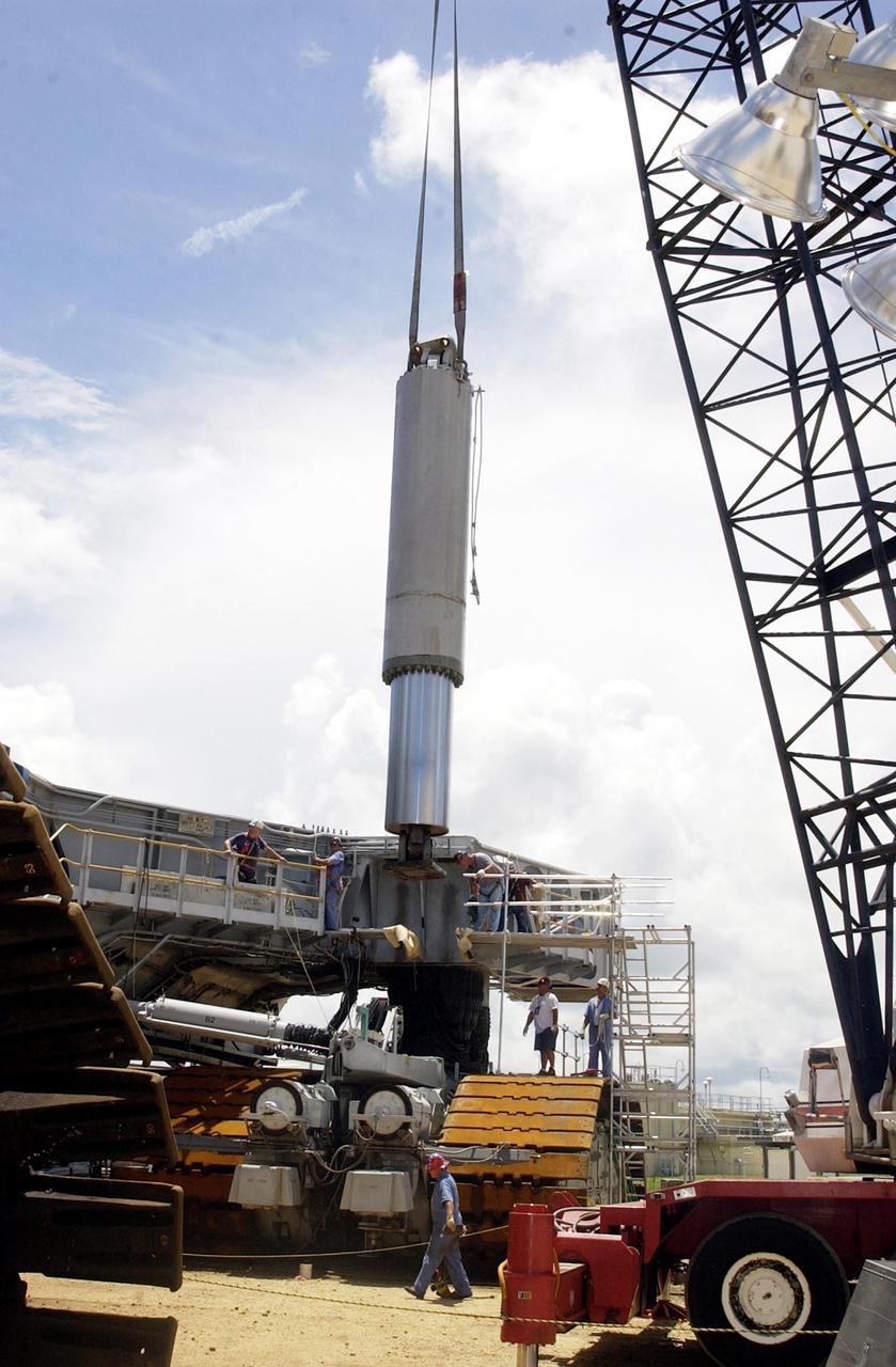 KENNEDY SPACE CENTER, FLA. -- A crane lowers a jacking, equalization and leveling (JEL) cylinder and bearing from Crawler-Transporter No. 2 to a position on the ground. During routine maintenance inspections last week, technicians removed two of the 16 JEL cylinders on the crawler to gain access to the bearings and found three of the four bearings cracked. Further eddy current inspections indicated that cracks are present on 15 of the bearings. There are 16 cylinders and 32 bearings per crawler. Engineers are evaluating the situation to determine the cause of the cracks and an appropriate solution to the problem.