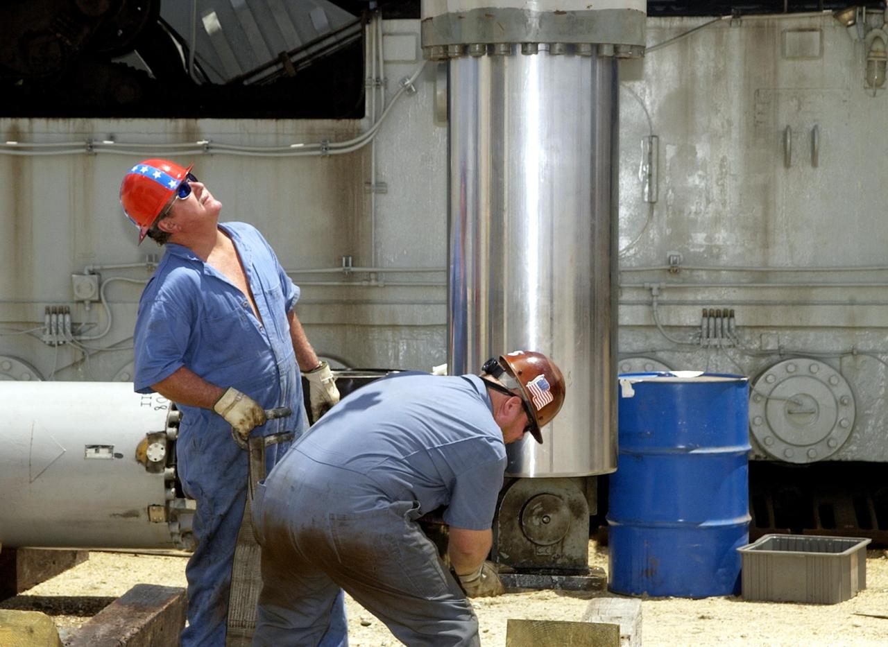KENNEDY SPACE CENTER, FLA. -- Technicians closely monitor a jacking, equalization and leveling (JEL) cylinder and bearing from Crawler-Transporter No. 2 as it lowered by a crane to a position on the ground.  During routine maintenance inspections last week, technicians removed two of the 16 JEL cylinders on the crawler to gain access to the bearings and found three of the four bearings cracked. Further eddy current inspections indicated that cracks are present on 15 of the bearings. There are 16 cylinders and 32 bearings per crawler. Engineers are evaluating the situation to determine the cause of the cracks and an appropriate solution to the problem.