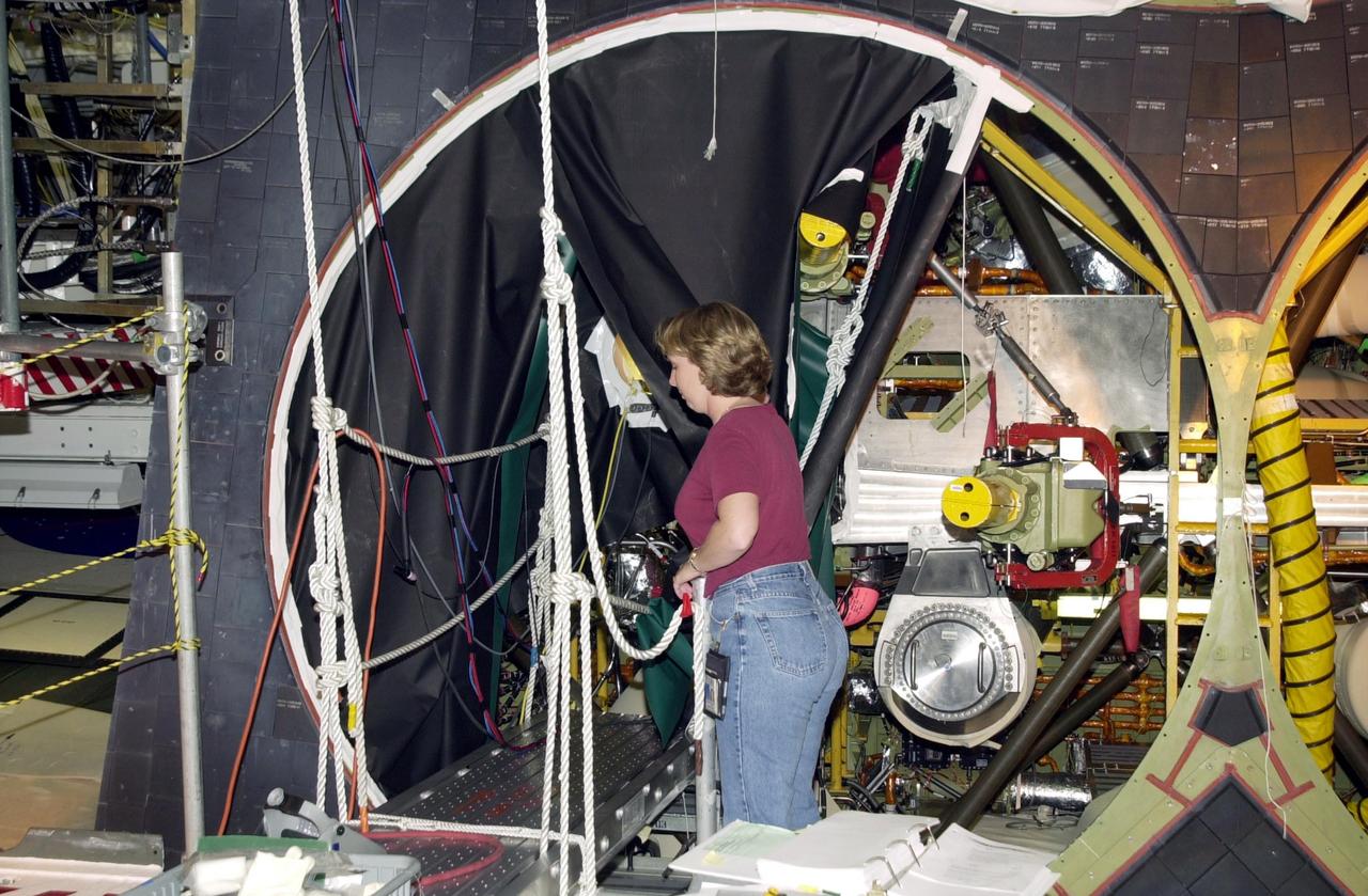 KENNEDY SPACE CENTER, FLA. -- Kristin Rumpf, with United Space Alliance - Main Propulsion System Engineering, looks over part of Endeavour before welding of the flow liner begins. Endeavour is scheduled to fly on mission STS-113 in November. The mission payload is the P1 Integrated Truss Structure, the first portside truss to go to the International Space Station, and will be attached to the central truss segment, S0, on the Station. Also additional cooling radiators will be delivered but will remain stowed until flight 12A.1.