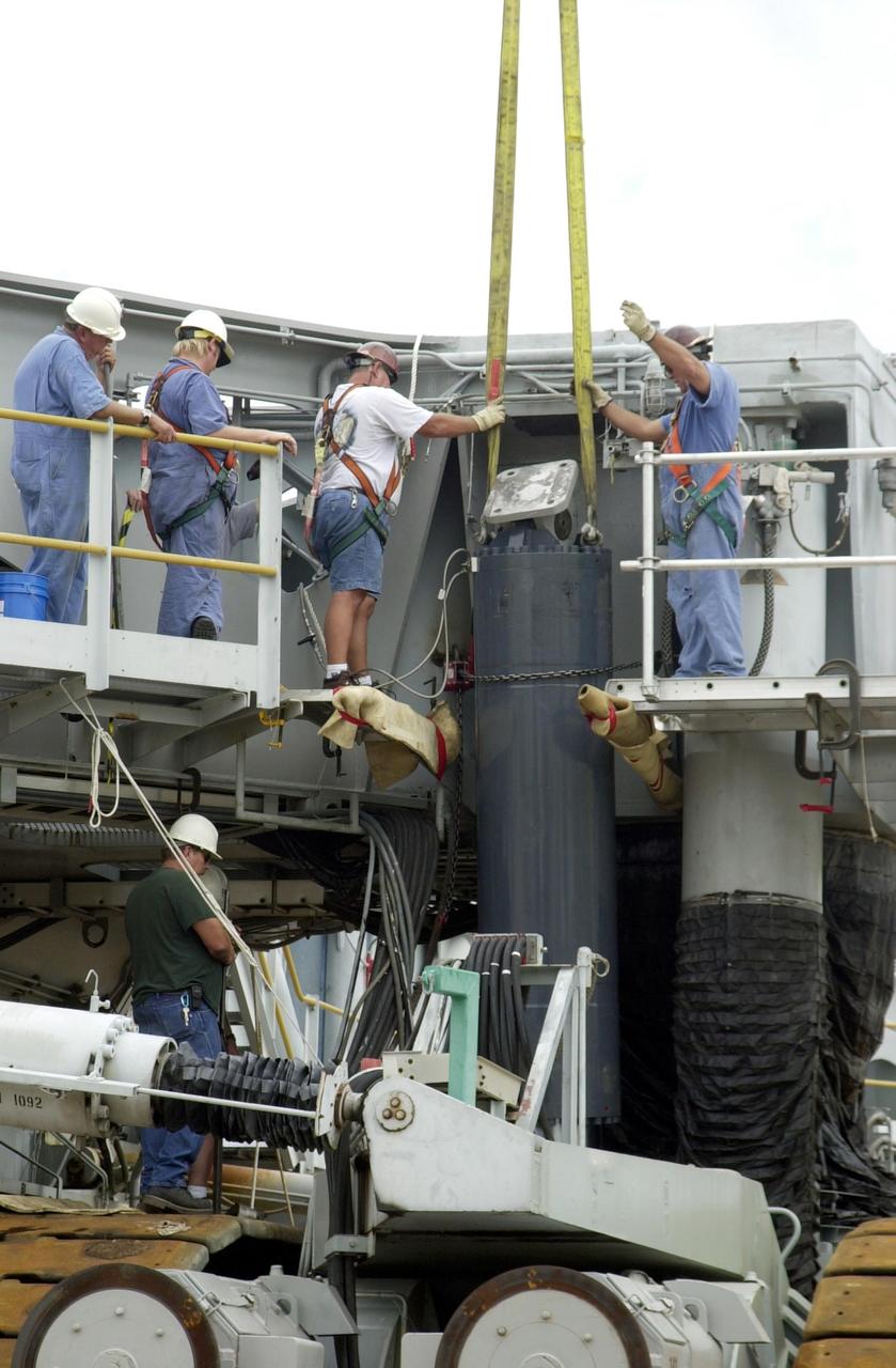 KENNEDY SPACE CENTER, FLA. --  Workers on Crawler Transporter No. 2 help guide a repaired Jacking, Equalization and Leveling (JEL) cylinder into place. There are 16 cylinders and 32 bearings per crawler.  During recent routine maintenance inspections, technicians removed two of the 16 JEL cylinders on the crawler to gain access to the bearings and found three of the four bearings cracked.  Further eddy current inspections indicated that cracks were present on 15 of the bearings. Technicians have removed and replaced 14 of the bearings on  CT-2, which is being repaired in order to enable Atlantis' rollout for mission STS-112, scheduled for launch no earlier than Oct. 2.