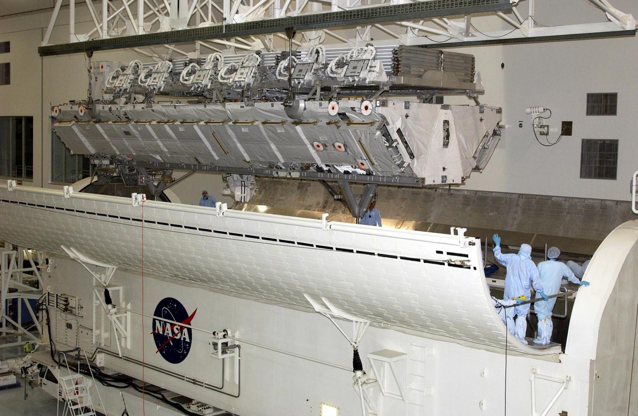KENNEDY SPACE CENTER, FLA. - Workers inside the payload canister watch the S1 Integrated Truss Structure as it is lowered toward them. The canister will transport the truss to Atlantis. The first starboard truss segment, the S1 will be attached to the Central truss segment, the S0 Truss, on the International Space Station during mission STS-112. Atlantis is scheduled to launch no earlier than Oct. 2.
