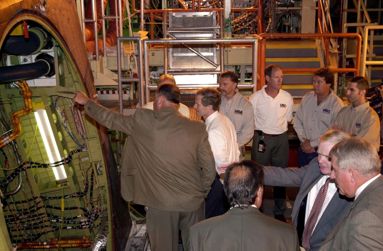 KENNEDY SPACE CENTER, FLA. - Bob Herman,chief engineer, Ground Operations for United Space Alliance (USA), shows U.S. Sen. Bill Nelson (center) part of orbiter Atlantis. Nelson was at KSC to present gold seal Senate certificates to the Flow Liner Inspection & Repair team for their part in finding the cracks in orbiter flow liners and repairing them. Team members are (behind Herman and Nelson, left to right) Mike Young, Jerry Goudy, Rick Beckwith, Tony Nesotas and David Strait. Goudy performed arc welding on one of Atlantis' flow liners; Strait found the original crack. In the foreground are Shuttle Engineering Director, USA, Mark Nappi; Center Director Roy Bridges; and vice president and deputy program manager, Florida Operations, USA, Bill Pickavance.
