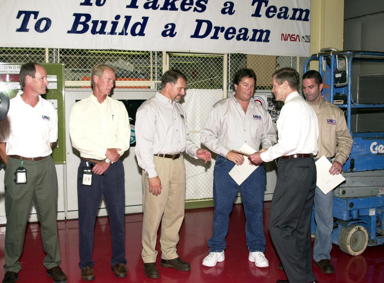 KENNEDY SPACE CENTER, FLA. -- U.S. Sen. Bill Nelson (front) presents gold seal Senate certificates to the Flow Liner Inspection & Repair team for their work on repairing the flow liners on the orbiters.   The team (background) comprises (left to right) Rick Beckwith, STR engineer; Mike Young, MPS engineer; Jerry Goudy, welder; Tony Nesotas, OFP-2 aft technician; and David Strait, OPF-2 orbiter inspector.  Strait first spotted the fuel-line crack; Goudy performed arc welding on one of Atlantis' flow liners. 