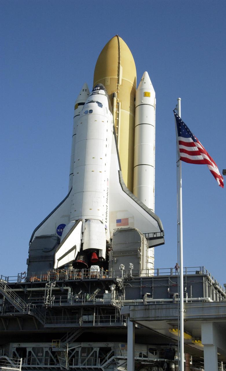 KENNEDY SPACE CENTER, FLA. --  After an early morning rollout, Space Shuttle Atlantis, atop the Mobile Launcher Platform, passes by the American flag as it moves through the gate at the launch pad. After being stacked with its solid rocket boosters and external tank, Atlantis began its rollout to Launch Pad 39B at 2:27 a.m. EDT in preparation for launch to the International Space Station. The Shuttle arrived at the Pad and was hard down at 9:38 a.m. Launch is scheduled no earlier than Oct. 2 for mission STS-112, the 15th assembly flight to the International Space Station.  Atlantis will carry the S1 Integrated Truss Structure, which will be attached to the central truss segment, the S0 truss, during the mission.    