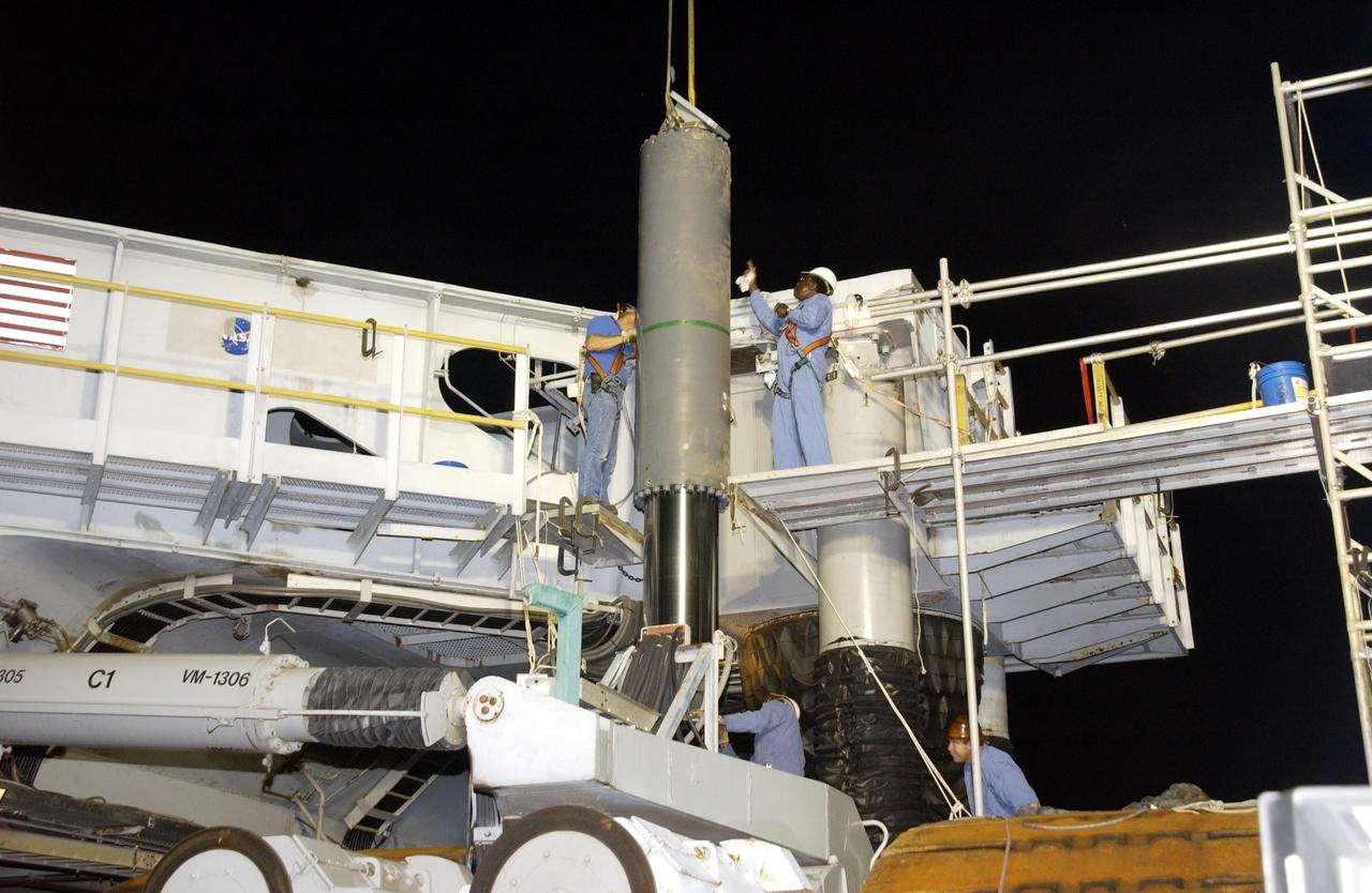 KENNEDY SPACE CENTER, FLA. --  Workers help guide the final Jacking, Equalization and Leveling (JEL) cylinder into place on Crawler Transporter No. 2 (CT-2) for installation. During recent routine maintenance inspections, cracks were found on four bearings in two JEL cylinders. Further eddy current inspections indicated that cracks were present on 15 bearings. There are 16 cylinders and 32 bearings per crawler. CT-2 was repaired in order to enable Atlantis' rollout for mission STS-112, scheduled for launch no earlier than Oct. 2.    