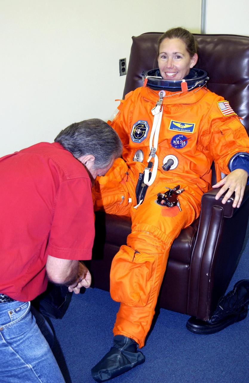 KENNEDY SPACE CENTER, Fla. - STS-112 Mission Specialist Sandra Magnus gets help donning her boots during suit check,  part of Terminal Countdown Demonstration Test activities.   The TCDT also includes emergency egress training and a simulated launch countdown.  The mission aboard Space Shuttle Atlantis  is scheduled to launch no earlier than Oct. 2, between 2 and 6 p.m. EDT.  STS-112 is the 15th assembly mission to the International Space Station.  Atlantis will be carrying the S1 Integrated Truss Structure, the first starboard truss segment.  The S1 will be attached to the central truss segment, S0, during the 11-day mission.  Magnus will serve as one of two operators of the Canadarm2 robotic arm for S1 truss installation and during three scheduled spacewalks.  STS-112 is her first Shuttle flight.