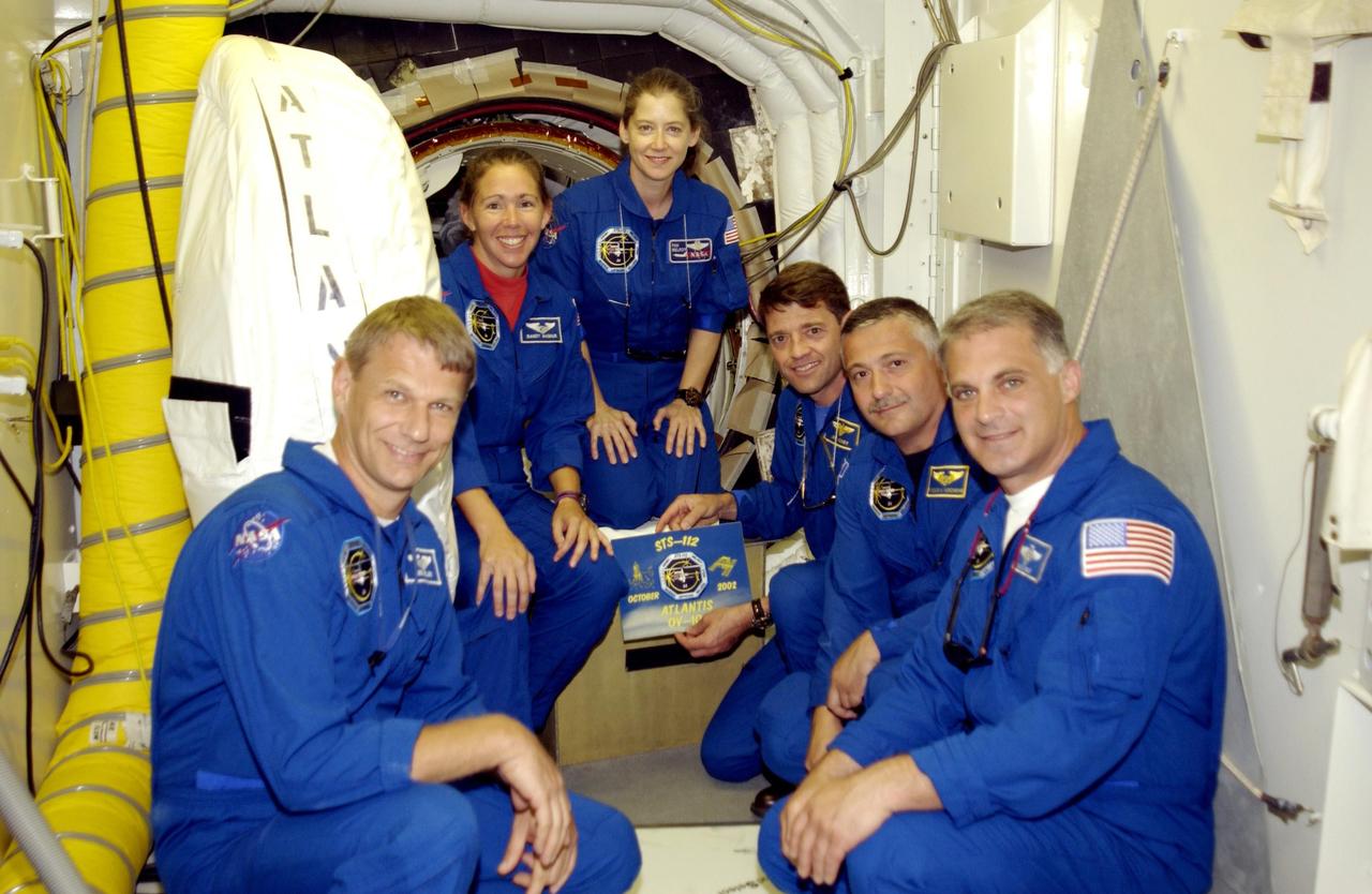 KENNEDY SPACE CENTER, FLA. --  The STS-112 crew pauses for a photo in the White Room during Terminal Countdown Demonstration Test activities.  From left, clockwise, are Mission Specialists Piers Sellers and Sandra Magnus, Pilot Pamela Melroy, Commander Jeffrey Ashby and Mission Specialists Fyodor Yurchikhin and David Wolf.  Ashby is holding the mission insignia.  Yurchikhin is with the Russian Space Agency. Mission STS-112 aboard Space Shuttle Atlantis is scheduled to launch no earlier than Oct. 2, between 2 and 6 p.m. EDT.  STS-112 is the 15th assembly mission to the International Space Station.  Atlantis will be carrying the S1 Integrated Truss Structure, the first starboard truss segment, to be attached to the central truss segment, S0, and the Crew and Equipment Translation Aid (CETA) Cart A.  The CETA is the first of two human-powered carts that will ride along the ISS railway, providing mobile work platforms for future spacewalking astronauts.  