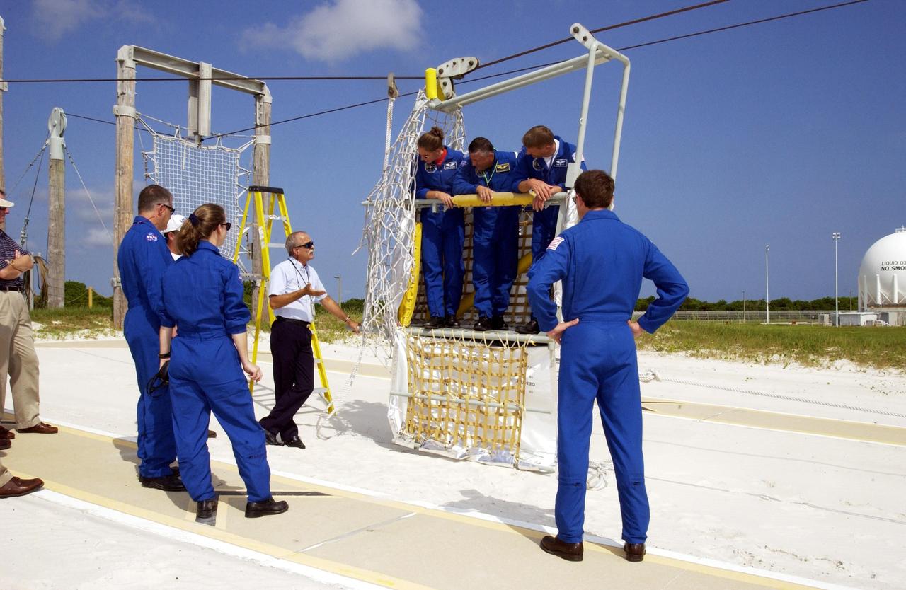 KENNEDY SPACE CENTER, FLA. -- The STS-112 crew listen to further instructions about emergency egress from the Shuttle using the slidewire basket.  In the basket are Mission Specialists Sandra Magnus, Fyodor Yurchikhin (with the Russian Space Agency), and Piers Sellers.  At left are Mission Specialist David Wolf and Pilot Pamela Melroy; at right is Commander Jeffrey Ashby.  The training is part of Terminal Countdown Demonstration Test activities, which include a simulated launch countdown.  Mission STS-112 aboard Space Shuttle Atlantis is scheduled to launch no earlier than Oct. 2, between 2 and 6 p.m. EDT.  STS-112 is the 15th assembly mission to the International Space Station.  Atlantis will be carrying the S1 Integrated Truss Structure, the first starboard truss segment, to be attached to the central truss segment, S0, and the Crew and Equipment Translation Aid (CETA) Cart A.  The CETA is the first of two human-powered carts that will ride along the ISS railway, providing mobile work platforms for future spacewalking astronauts.  