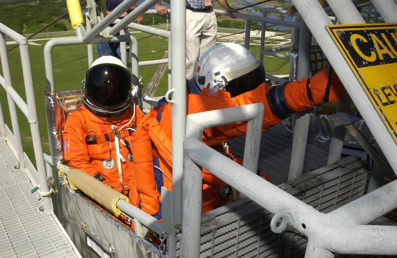 KENNEDY SPACE CENTER, FLA. - STS-112 Mission Specialist Sandra Magnus (left) sits in the slidewire basket basket on the 195-foot level of the Fixed Service Structure, Launch Pad 39B, while Mission Specialist Piers Sellers (right) reaches for the release lever. They and the rest of the crew are practicing emergency egress from the pad during Terminal Countdown Demonstration Test activities. Mission STS-112 aboard Space Shuttle Atlantis is scheduled to launch no earlier than Oct. 2, between 2 and 6 p.m. EDT.  STS-112 is the 15th assembly mission to the International Space Station.  Atlantis will be carrying the S1 Integrated Truss Structure, the first starboard truss segment, to be attached to the central truss segment, S0, and the Crew and Equipment Translation Aid (CETA) Cart A.  The CETA is the first of two human-powered carts that will ride along the ISS railway, providing mobile work platforms for future spacewalking astronauts.  