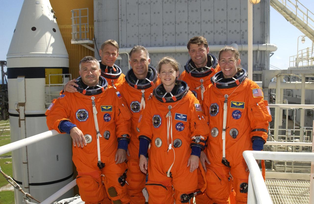 KENNEDY SPACE CENTER, FLA. - The STS-112 crew gathers for a group photo on the 215-foot level of the Fixed Service Structure.  From left are Mission Specialists Fyodor Yurchikhin, Piers Sellers and David Wolf; Pilot Pamela Melroy; Commander Jeffrey Ashby; and Mission Specialist Sandra Magnus.  Behind them at left is seen one of the white solid rocket boosters and the orange external tank on Space Shuttle Atlantis. Mission STS-112 is scheduled to launch no earlier than Oct. 2, between 2 and 6 p.m. EDT.  STS-112 is the 15th assembly mission to the International Space Station.  Atlantis will be carrying the S1 Integrated Truss Structure, the first starboard truss segment, to be attached to the central truss segment, S0, and the Crew and Equipment Translation Aid (CETA) Cart A.  The CETA is the first of two human-powered carts that will ride along the ISS railway, providing mobile work platforms for future spacewalking astronauts.  The 11-day mission is expected to conclude with a landing at KSC Oct. 13.     