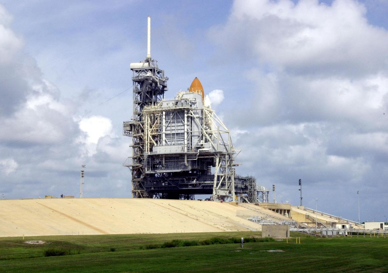 KENNEDY SPACE CENTER, FLA. - Only the tip of the orange external tank on Space Shuttle Atlantis is visible above the Rotating Service Structure surrounding Atlantis on Launch Pad 39B. The Shuttle is undergoing pre-launch preparations for mission STS-112, scheduled to launch Oct. 2, 2002. The sky above the Shuttle is filled with dark clouds sweeping over Florida from Hurricane Isidore.