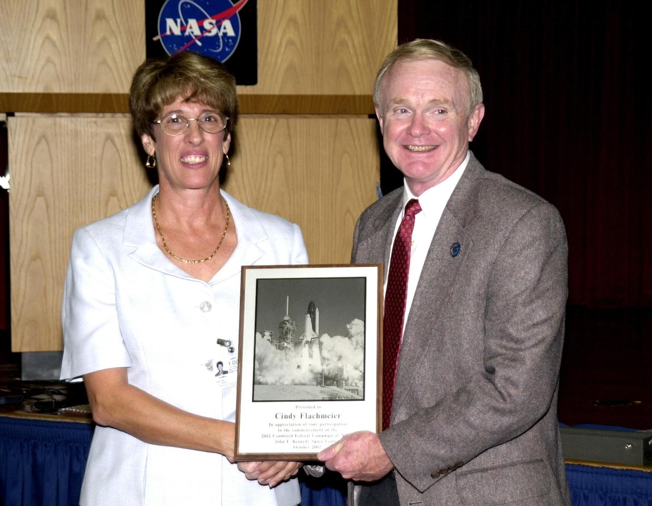 KENNEDY SPACE CENTER, FLA. - During Kennedy Space Center’s  2002 Combined Federal Campaign kickoff rally at the Training Auditorium, Oct. 1, 2002, Center Director, Roy D. Bridges Jr., presented guest speaker Cindy Flachmeier, program coordinator, Domestic Violence Program, Salvation Army of North/Central Brevard, with an appreciation plaque. The CFC is NASA’s agencywide annual fundraising campaign for approved worthy causes that runs through Oct. 31, 2002. This year’s slogan is “Promoting Hope…through Generosity.”