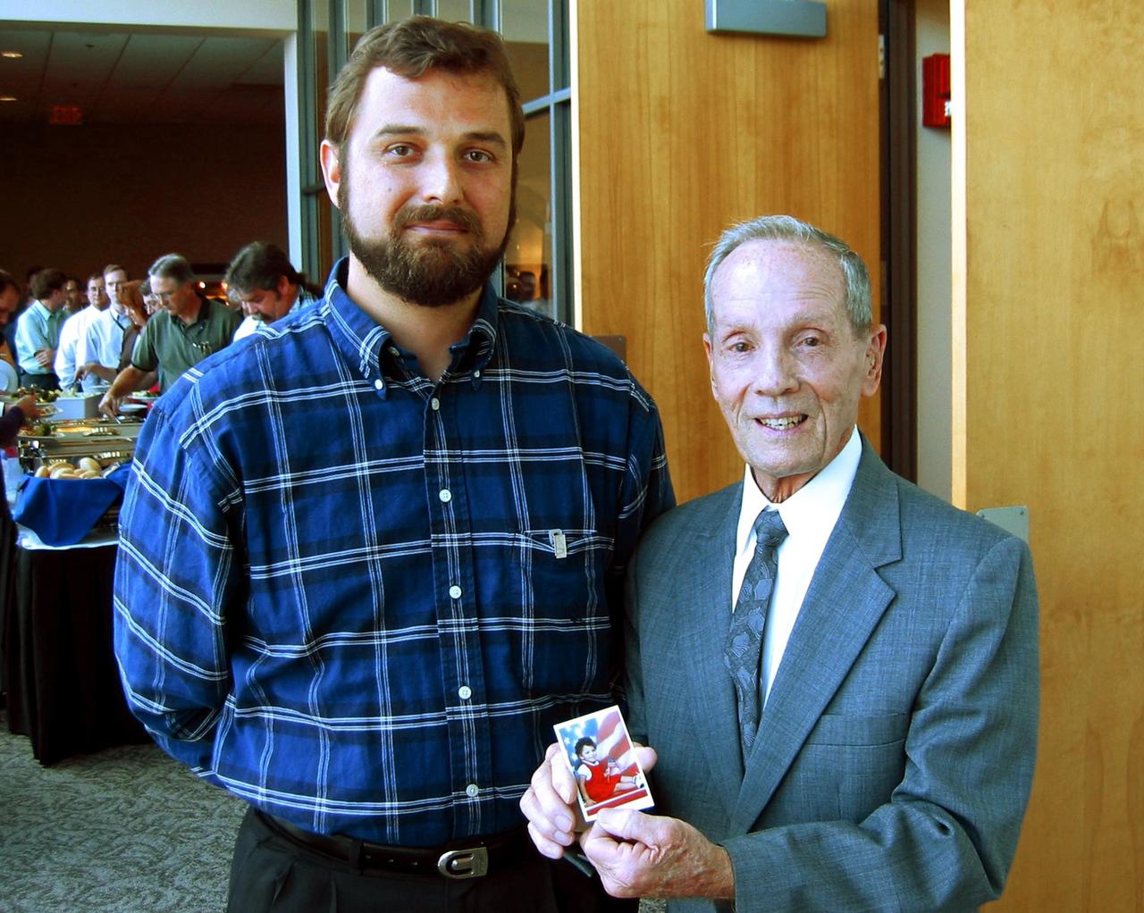 KENNEDY SPACE CENTER, FLA. -- Adam Kissiah (right), a retired NASA-KSC engineer shows a photo of Allan Dianic's daughter, who has benefited from a cochlear implant that Kissiah developed while at NASA.  Dianic (left) is a software engineer with ENSCO.  Kissiah received an exceptional category NASA Space Act Award for his 25-year-old technology breakthrough during a technology awards luncheon held at the KSC Visitor Complex Debus Center.   The award included a monetary award and a certificate signed by the NASA Administrator. Space Act Awards provide official recognition and grant equitable monetary awards for inventions and scientific and technical contributions that have helped achieve NASA's aeronautical and space goals.