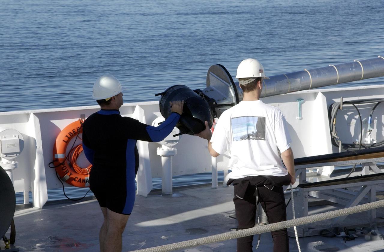 KENNEDY SPACE CENTER, FLA. -- Workers on the deck of the Liberty Star, one of NASA's solid rocket booster retrieval ships, oversee the lifting of sonar mapping equipment from the deck toward the side of the ship. The equipment will be attached to the ship's hull for an eight-day expedition surveying deep-water coral reefs on the Oculina Banks off eastern Florida. NASA joins the National Oceanic and Atmospheric Administration (NOAA) and other ocean scientists for the sophisticated mapping system that will provide the first high-resolution, three-dimensional map of the Oculina Banks. The survey results are expected to guide another expedition in Spring 2003, using NASA's ship, when the reef fish spawn. Also used will be NASA's underwater robot and an acoustic hydrophone system for listening to fish and vessel noise. Dive sites will be chosen based on the new charts.