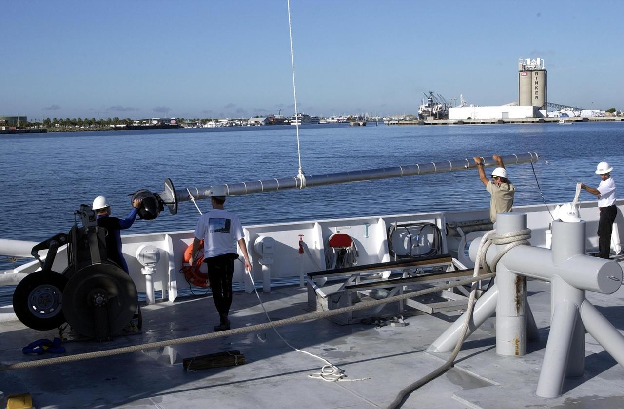 KENNEDY SPACE CENTER, FLA. -- Workers on the deck of the Liberty Star, one of NASA's solid rocket booster retrieval ships, help guide sonar mapping equipment toward the side of the ship.  The equipment will be attached to the ship's hull for an eight-day expedition surveying deep-water coral reefs on the Oculina Banks off eastern Florida.  NASA joins the National Oceanic and Atmospheric Administration (NOAA) and other ocean scientists for the sophisticated mapping system that will provide the first high-resolution, three-dimensional map of the Oculina Banks.  The survey results are expected to guide another expedition in Spring 2003, using NASA's ship, when the reef fish spawn.  Also used will be NASA's underwater robot and an acoustic hydrophone system for listening to fish and vessel noise.  Dive sites will be chosen based on the new charts.