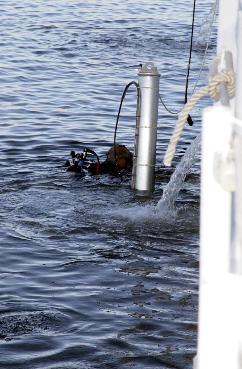 KENNEDY SPACE CENTER, FLA. --  A diver helps lower sonar mapping equipment into the water alongside the Liberty Star, one of NASA's solid rocket booster retrieval ships. The equipment will be attached to the ship's hull for an eight-day expedition surveying deep-water coral reefs on the Oculina Banks off eastern Florida.  NASA joins the National Oceanic and Atmospheric Administration (NOAA) and other ocean scientists for the sophisticated mapping system that will provide the first high-resolution, three-dimensional map of the Oculina Banks.  The survey results are expected to guide another expedition in Spring 2003, using NASA's ship, when the reef fish spawn.  Also used will be NASA's underwater robot and an acoustic hydrophone system for listening to fish and vessel noise.  Dive sites will be chosen based on the new charts.