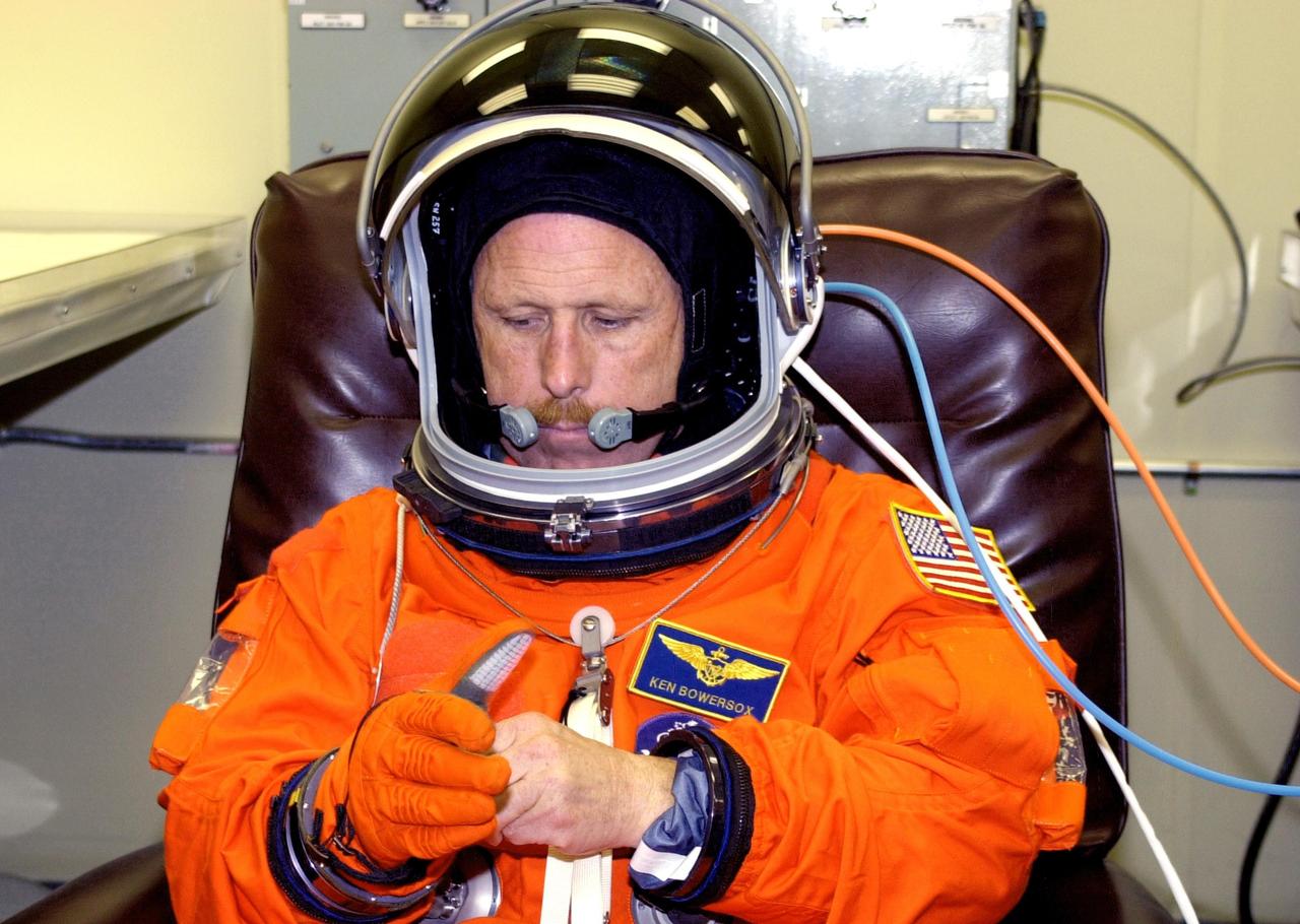 KENNEDY SPACE CENTER, FLA. -- Expedition 6 Commander Ken Bowersox adjusts his gloves during fit check of his launch and entry suit, part of Terminal Countdown Demonstration Test activities. He and the rest of the crew are preparing for the mission aboard Space Shuttle Endeavour, which is scheduled to launch Nov. 10.  The TCDT includes emergency egress training and a launch countdown. The Expedition 6 crew will travel on Space Shuttle Endeavour to the International Space Station to replace Expedition 5, returning to Earth after 4 months. The primary payloads on mission STS-113 are the first port truss segment, P1, and the Crew and Equipment Translation Aid (CETA) Cart B.   Once delivered, the P1 truss will remain stowed until flight 12A.1 in 2003 when it will be attached to the central truss segment, S0, on the Space Station.  Launch is scheduled for Nov. 10, 2002.