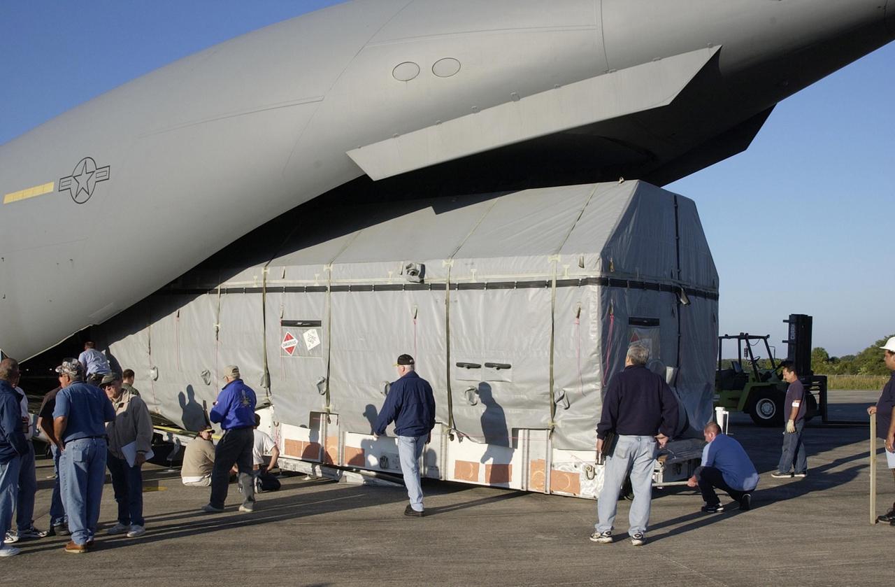 KENNEDY SPACE CENTER, FLA. --  The Tracking and Data Relay Satellite-J (TDRS-J) is being offloaded at the KSC Shuttle Landing Facility from an Air Force C-17 air cargo plane.   It will be transferred to the Spacecraft Assembly and Encapsulation Facility-2 (SAEF-2). TDRS-J weighs 3,338 pounds, but at launch will weigh 7,031 pounds when fully fueled with its propellants consisting of monomethylhydrazine fuel and nitrogen tetroxide oxidizer. The solar arrays, when deployed, will supply the spacecraft with up to 2,200 watts of power.  TDRS-J is the third in the current series of three Tracking and Data Relay Satellites designed to replenish the existing on-orbit fleet of six spacecraft, the first of which was launched in 1983. The Tracking and Data Relay Satellite System is the primary source of space-to-ground voice, data and telemetry for the Space Shuttle. It also provides communications with the International Space Station and scientific spacecraft in low-earth orbit such as the Hubble Space Telescope, and launch support for some expendable vehicles. This new advanced series of satellites will extend the availability of TDRS communications services until approximately 2017.  