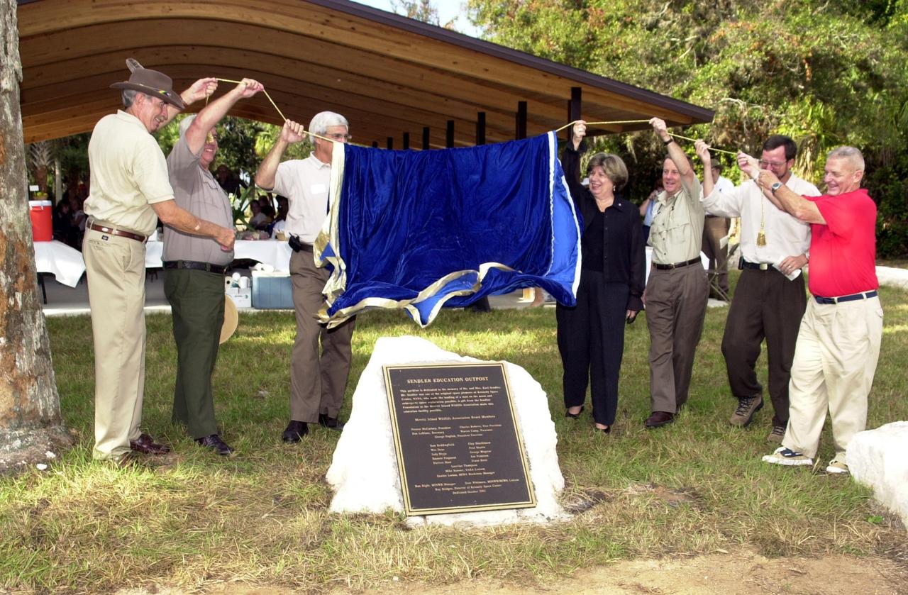 KENNEDY SPACE CENTER, FLA. -  Representatives from the Merritt Island National Wildlife Refuge (MINWR) and KSC unveil a plaque dedicating the Sendler Education Outpost, located at Dummit Cove on the Refuge.  Fourth from right is Acting Deputy Director JoAnn Morgan.  The outpost is a resource for environmental educational students in the Central Florida area.  It is named for Karl Sendler, a space pioneer and manager under Dr. Kurt Debus, KSC's first center director.  Funding for the facility was provided by the Merritt Island Wildlife Association with assistance from MINWR and Kennedy Space Center.